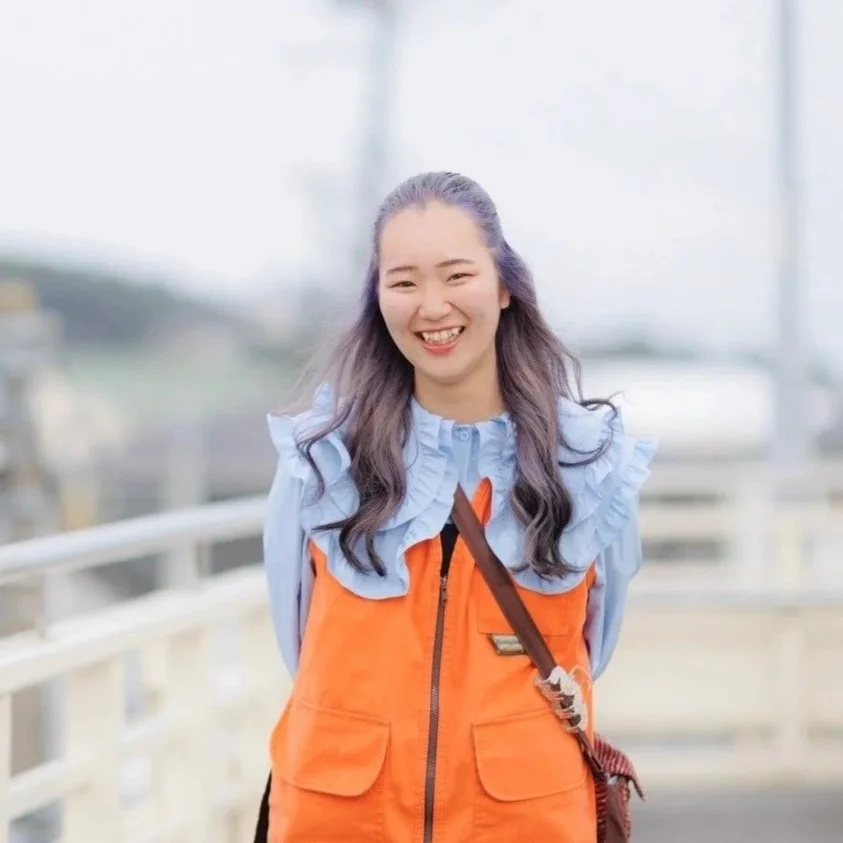 笑顔の若い女性が外でたたずんでいる。