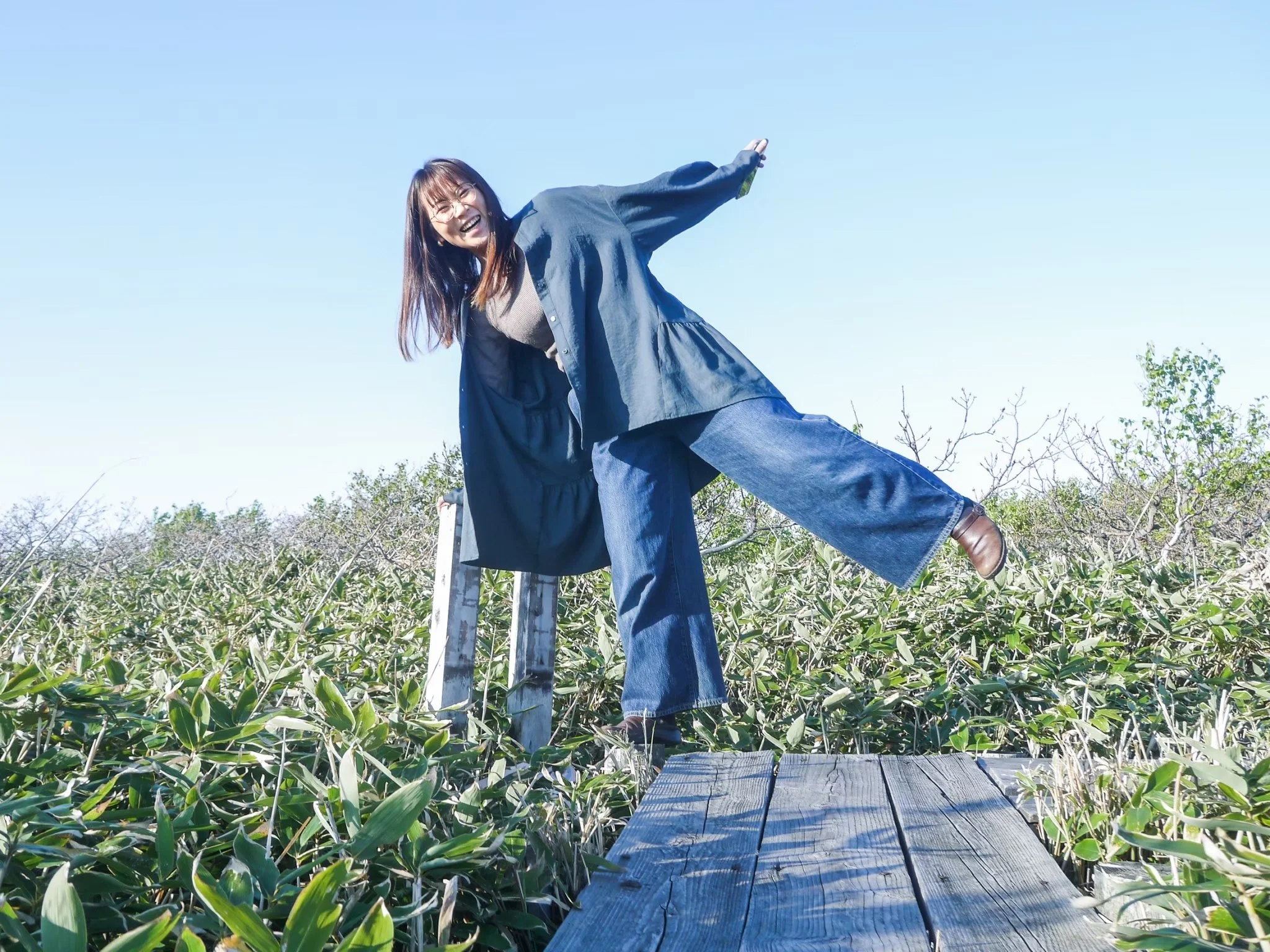 青空の下で笑っている女性が木製の階段の上に立っている。