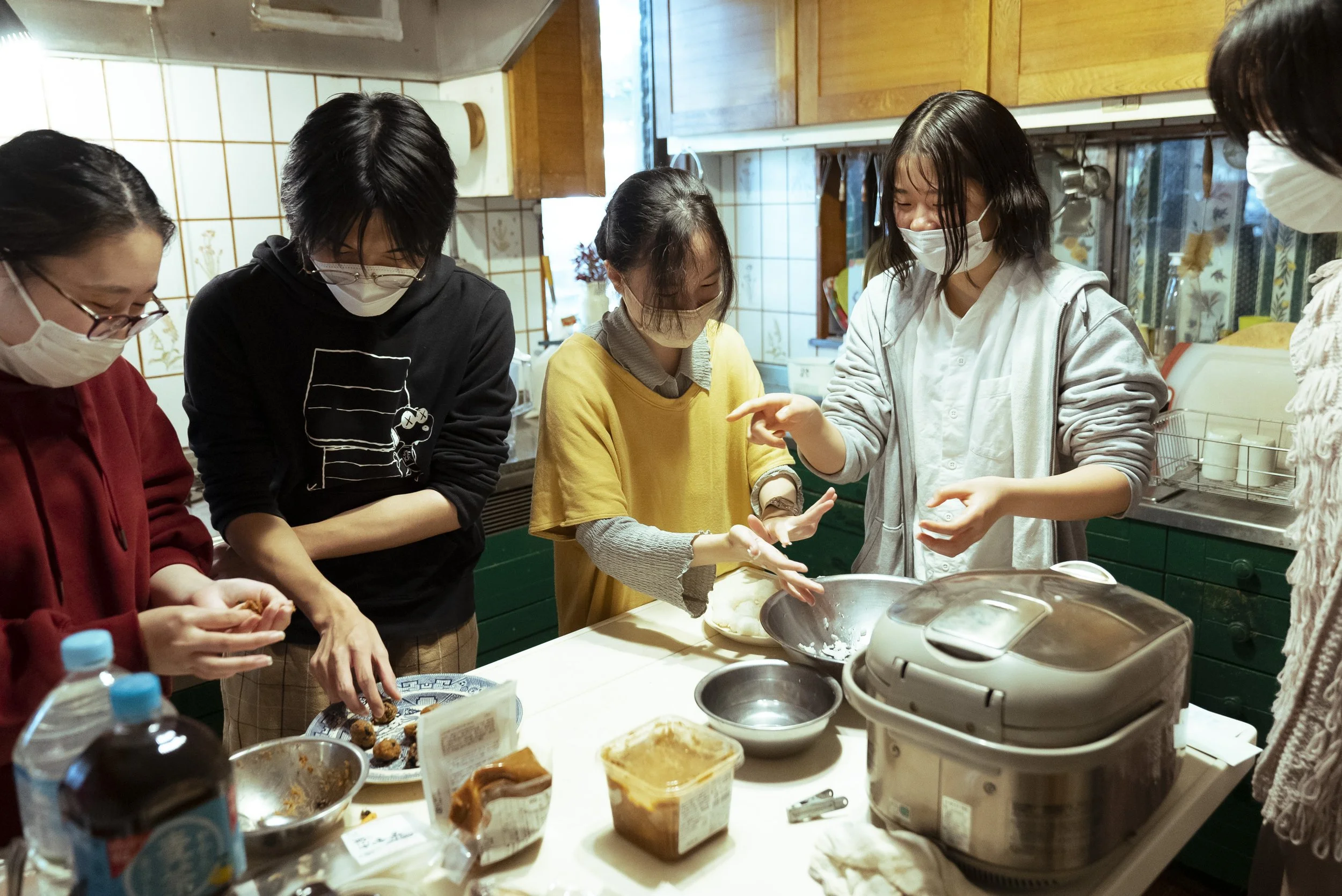 キッチンで料理をしている女性たちが協力して料理を作っている様子。