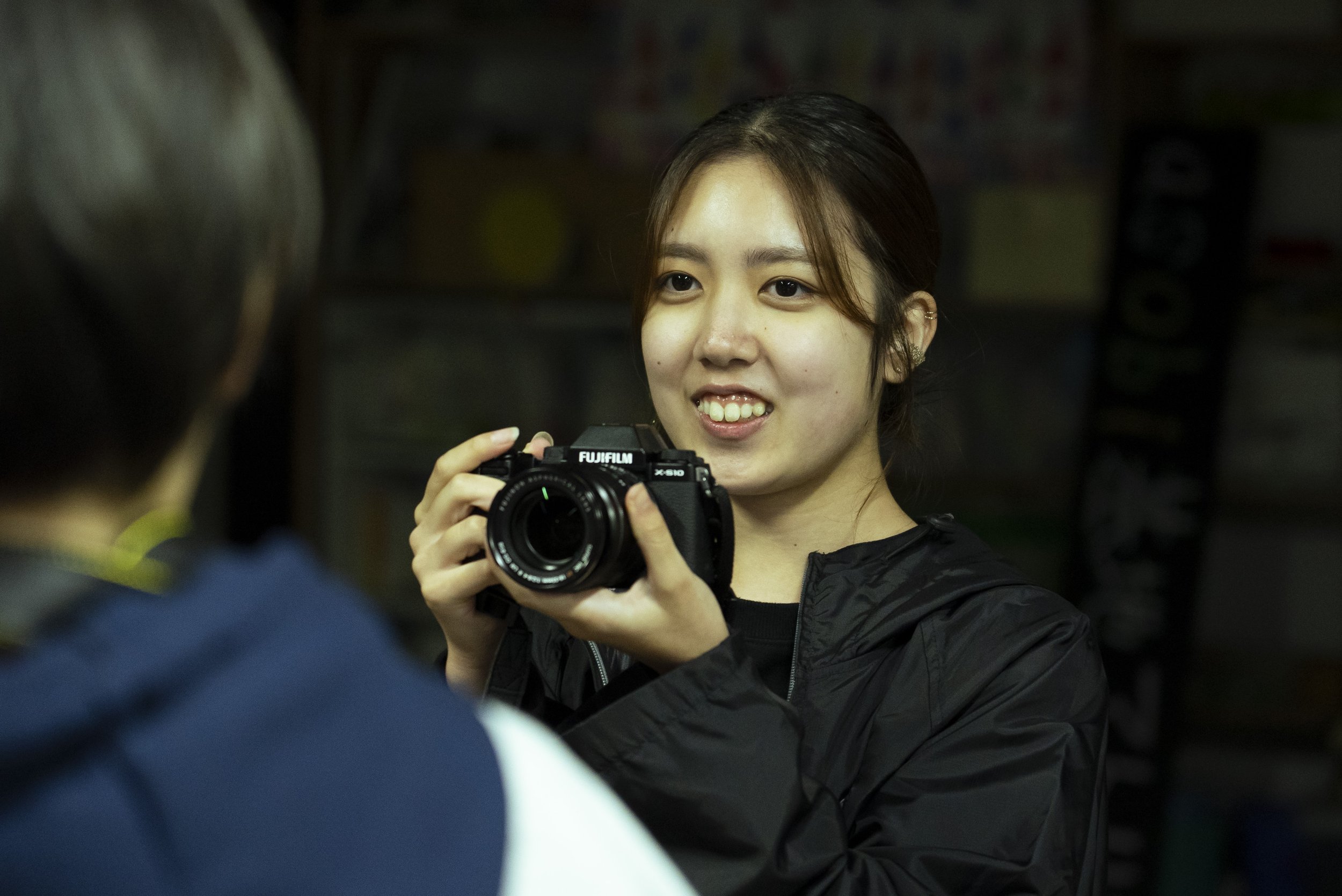 女性がカメラを持ちながら笑顔で写真を撮るシーン