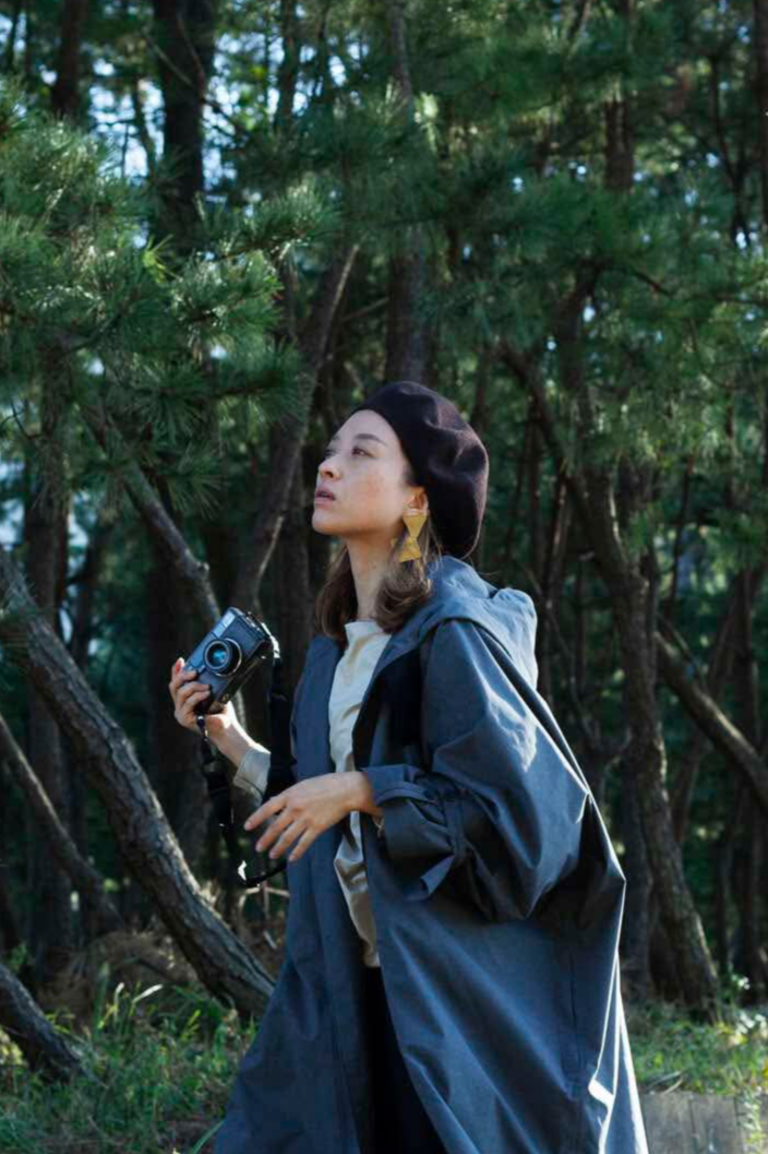 森の中でカメラを持った女性が立っている
