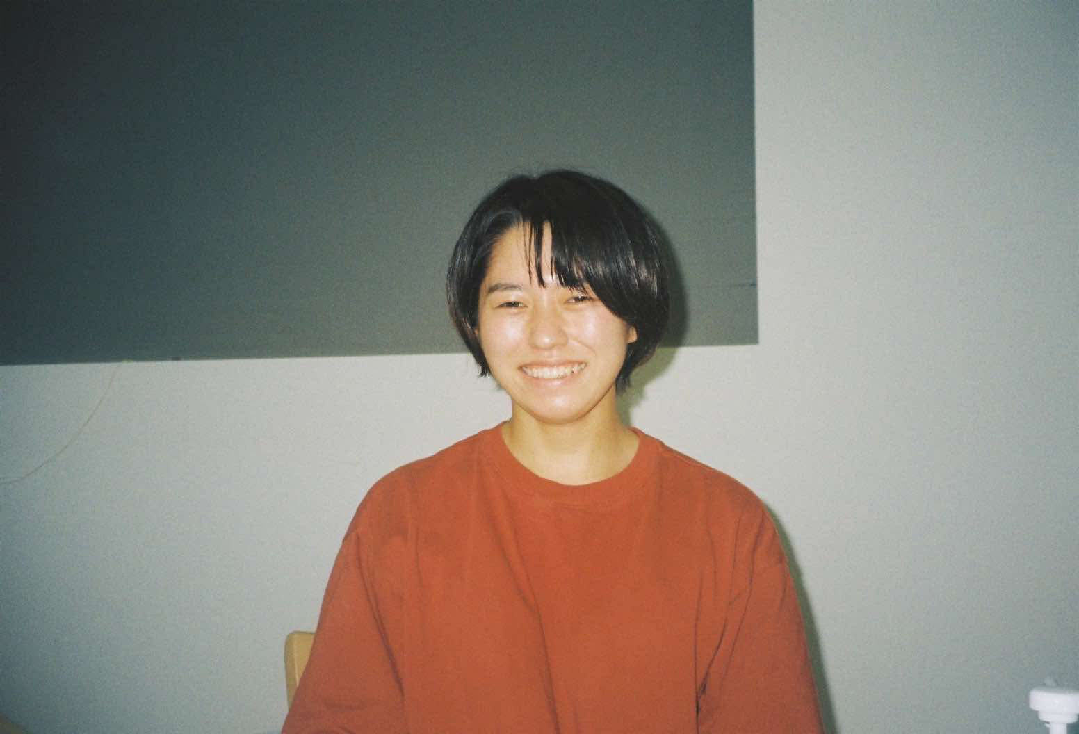 笑顔の女性が赤いトップスを着ている写真。