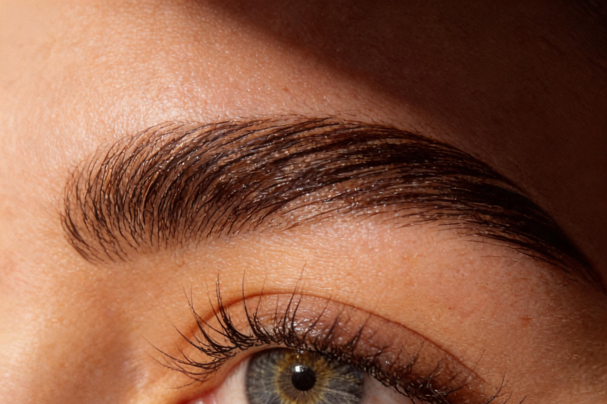 Nahaufnahme eines Auges mit braunem iris und geschminkten Wimpern.