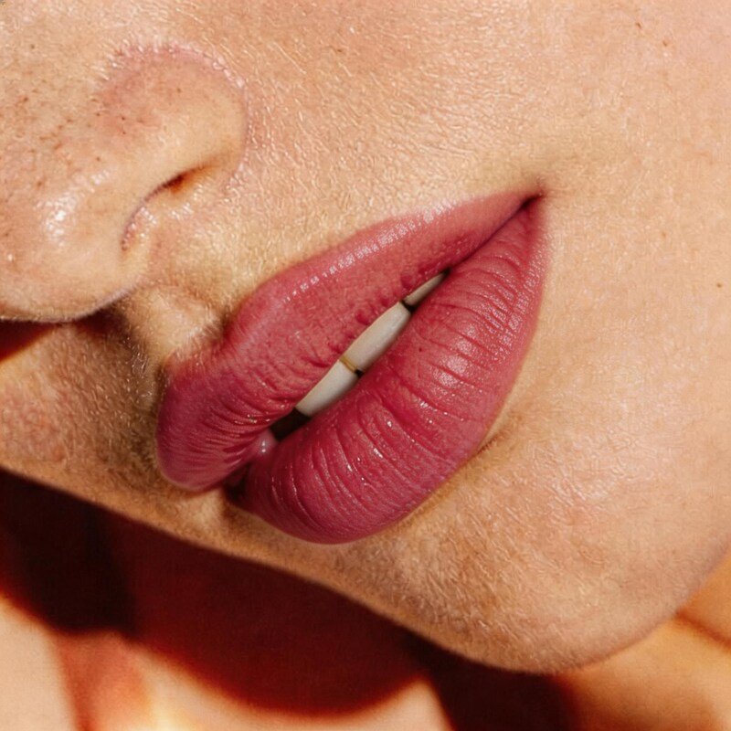 Nahaufnahme von Lippen und Nasenbereich einer Person, mit Fokus auf voll geschminkte Lippen und leicht geperlter Haut.