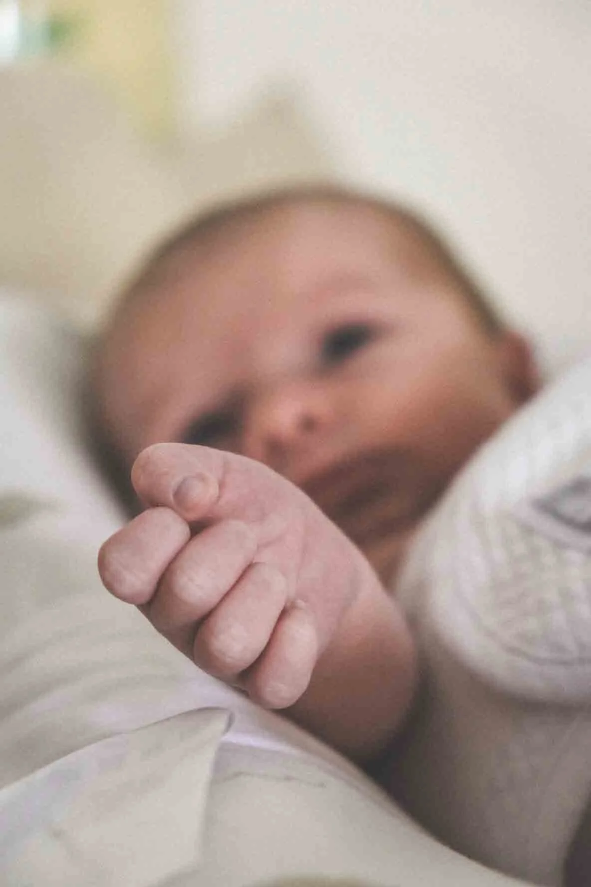 Un bébé qui regarde dans un miroir, montrant son visage flou et ses petits doigts en premier plan.