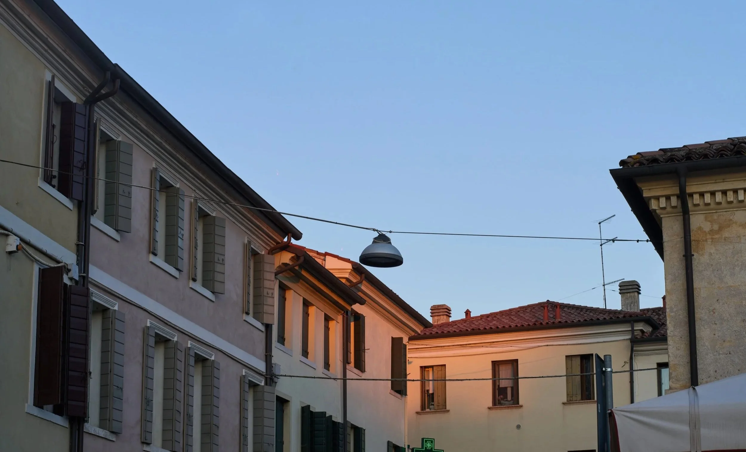 Edificio residenziale con finestre aperte, illuminato dal tramonto, sotto un cielo blu senza nuvole.