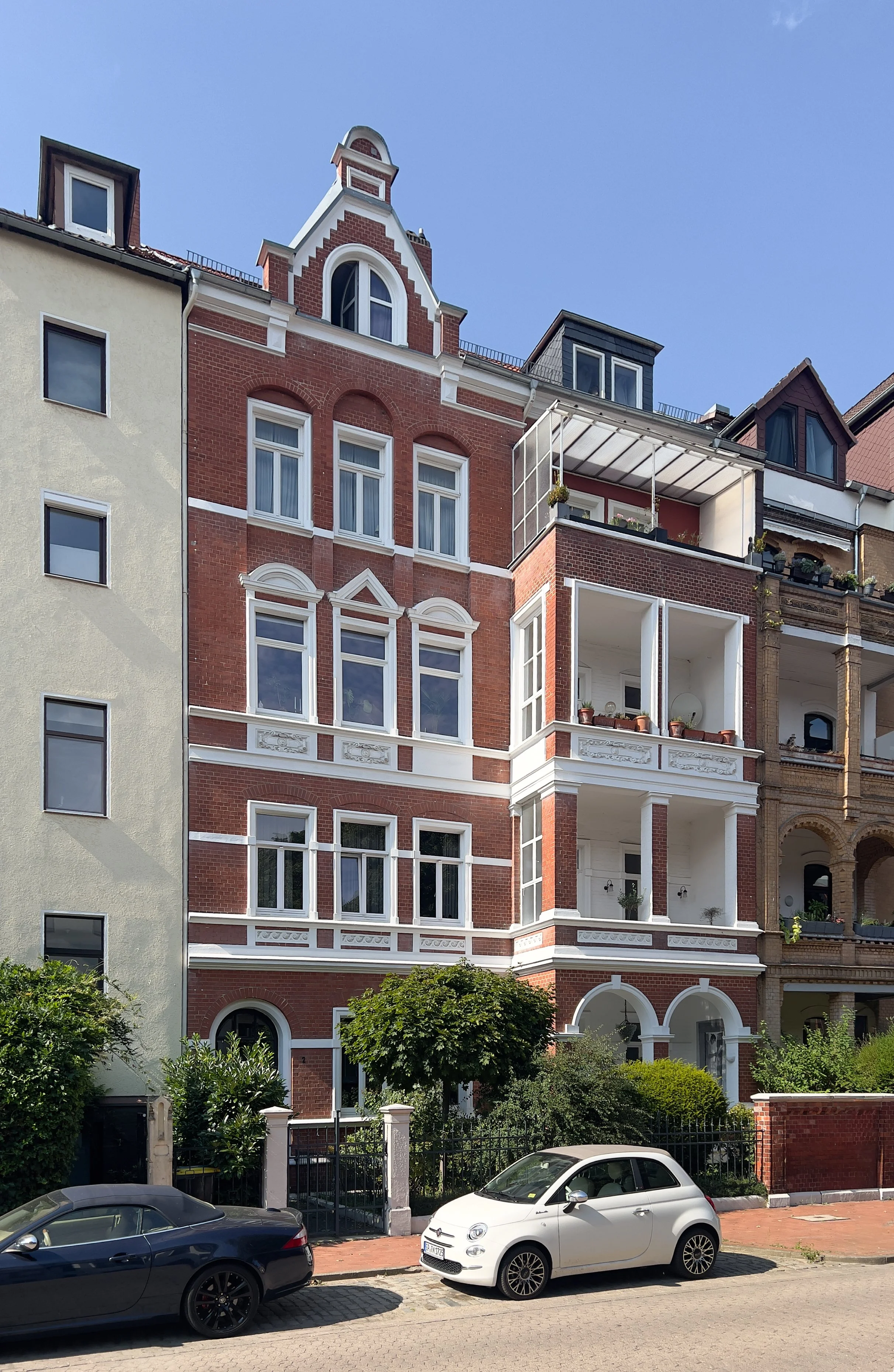 Ansicht von einem Altbau aus rotem Backstein und weißen Fassadendetails, welches saniert wurde.