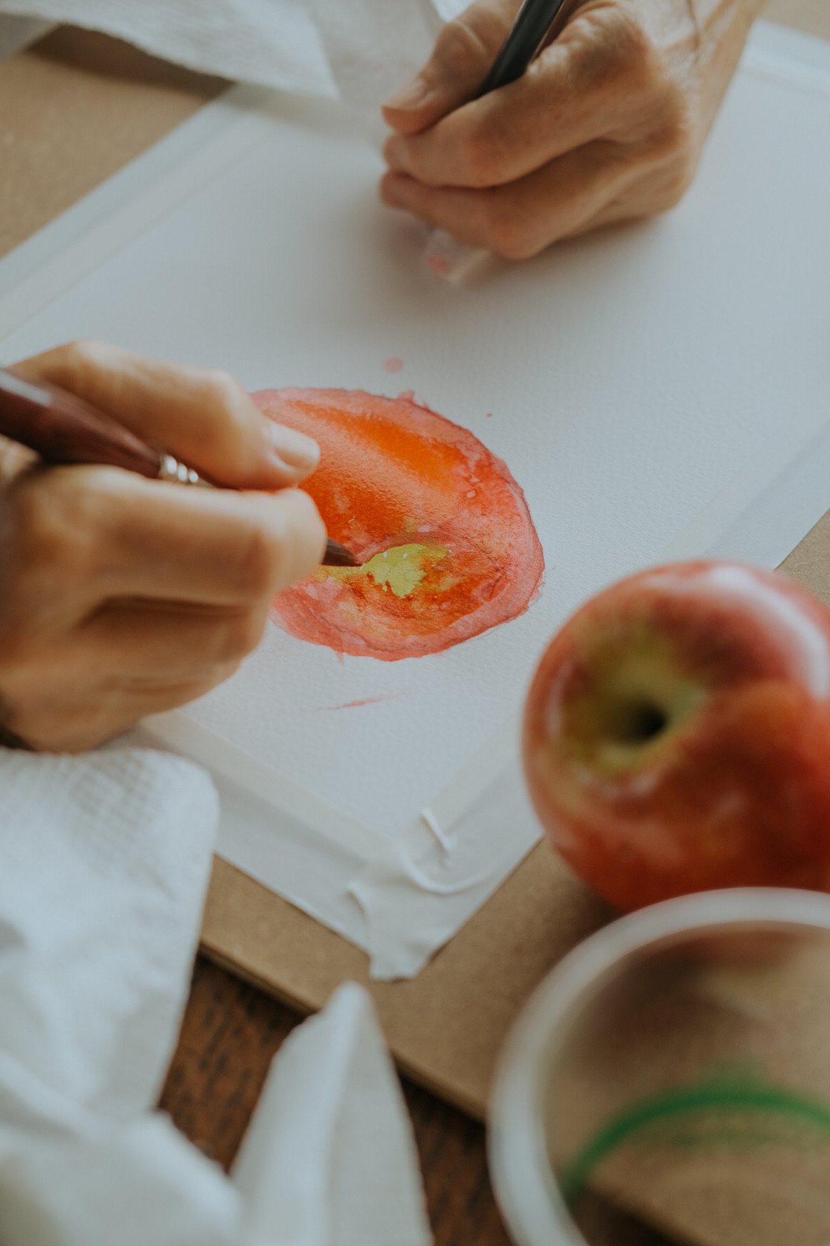 Person painting a watercolor of an apple at Rebecca Gottesman's beginner class.