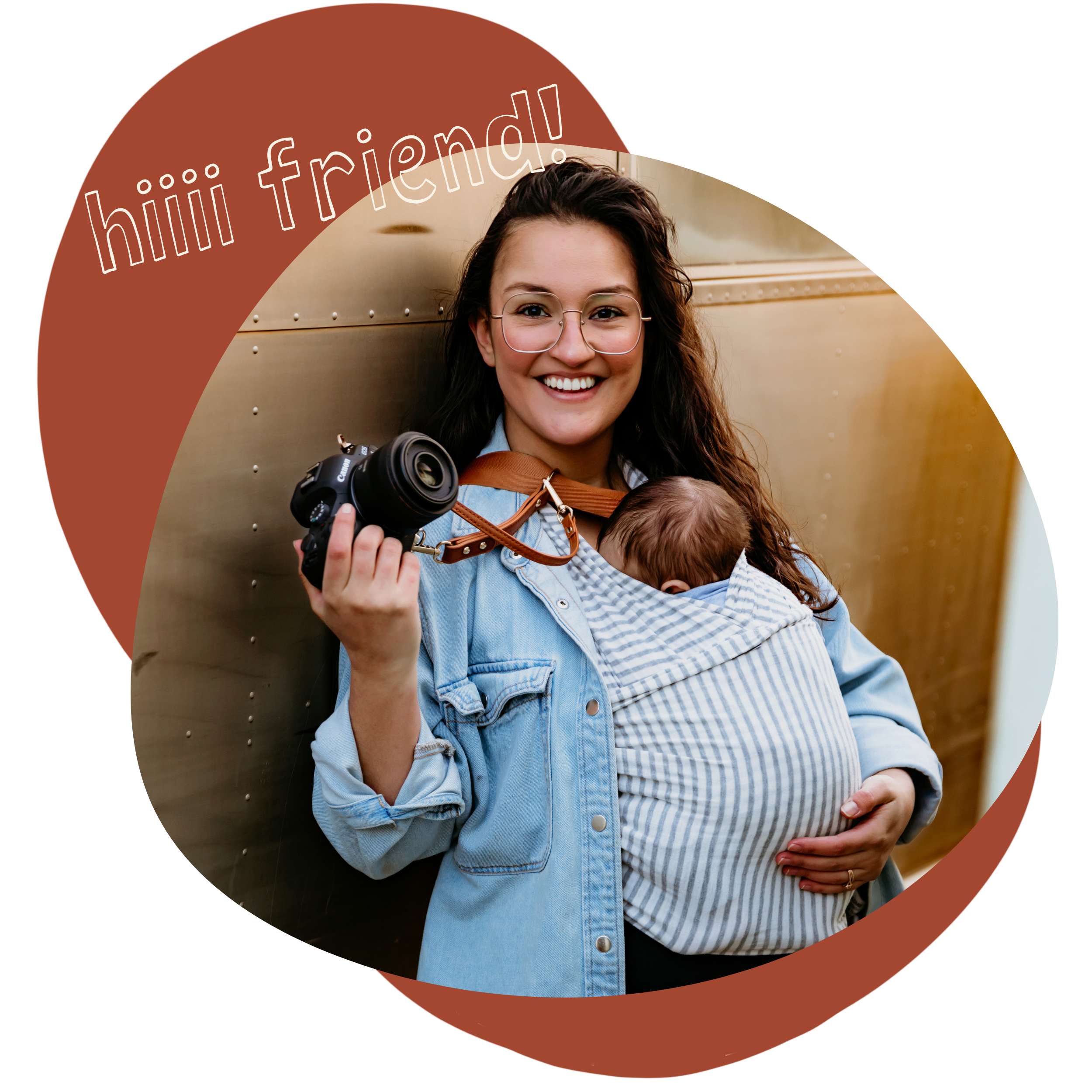 hi friend! Marina Anaya, a family photographer holding her camera on one hand and wearing her baby in a carrier