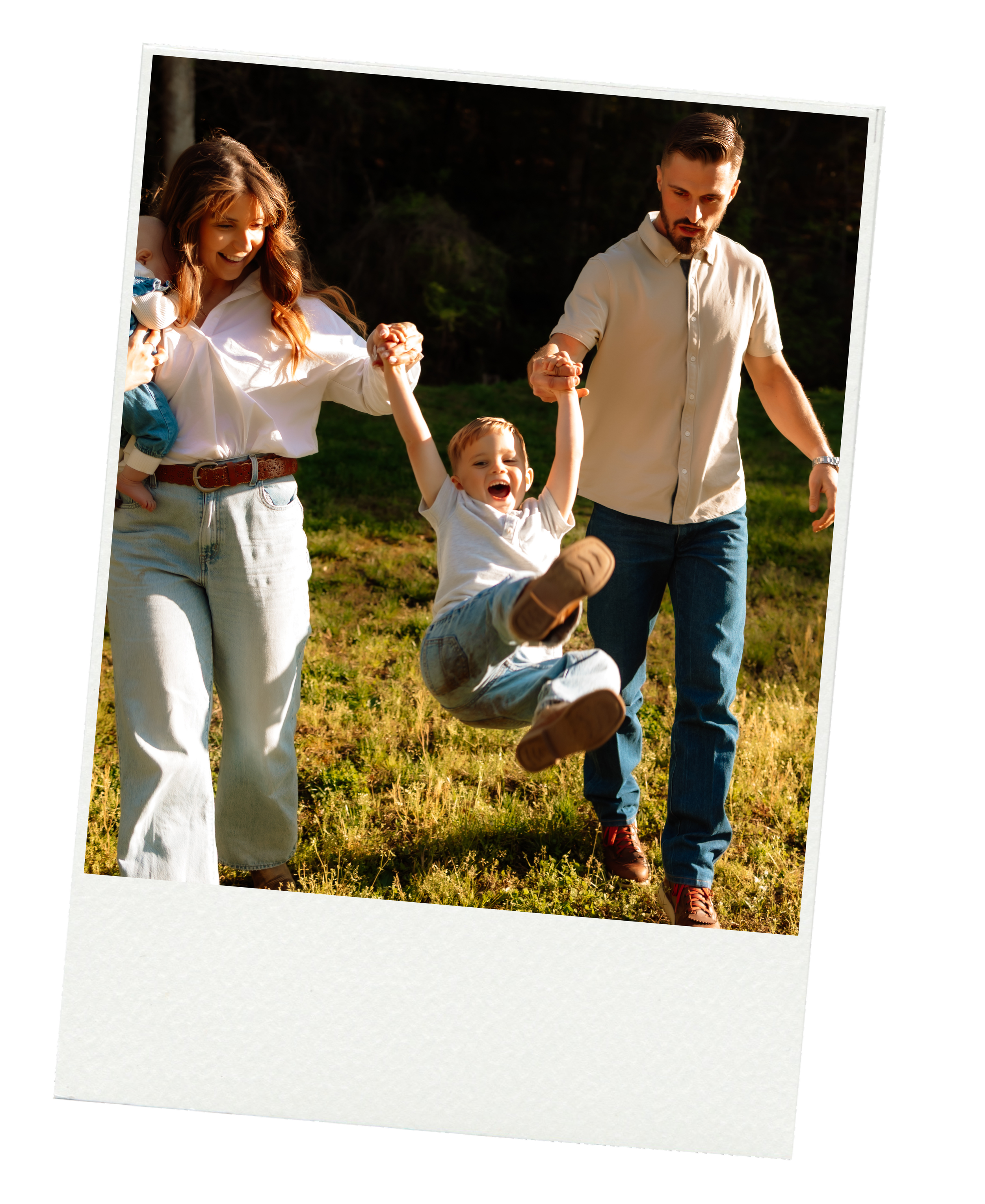 photo printed on a polaroid of a candid moment with a family where mom and dad are swinging their joyful son in the air