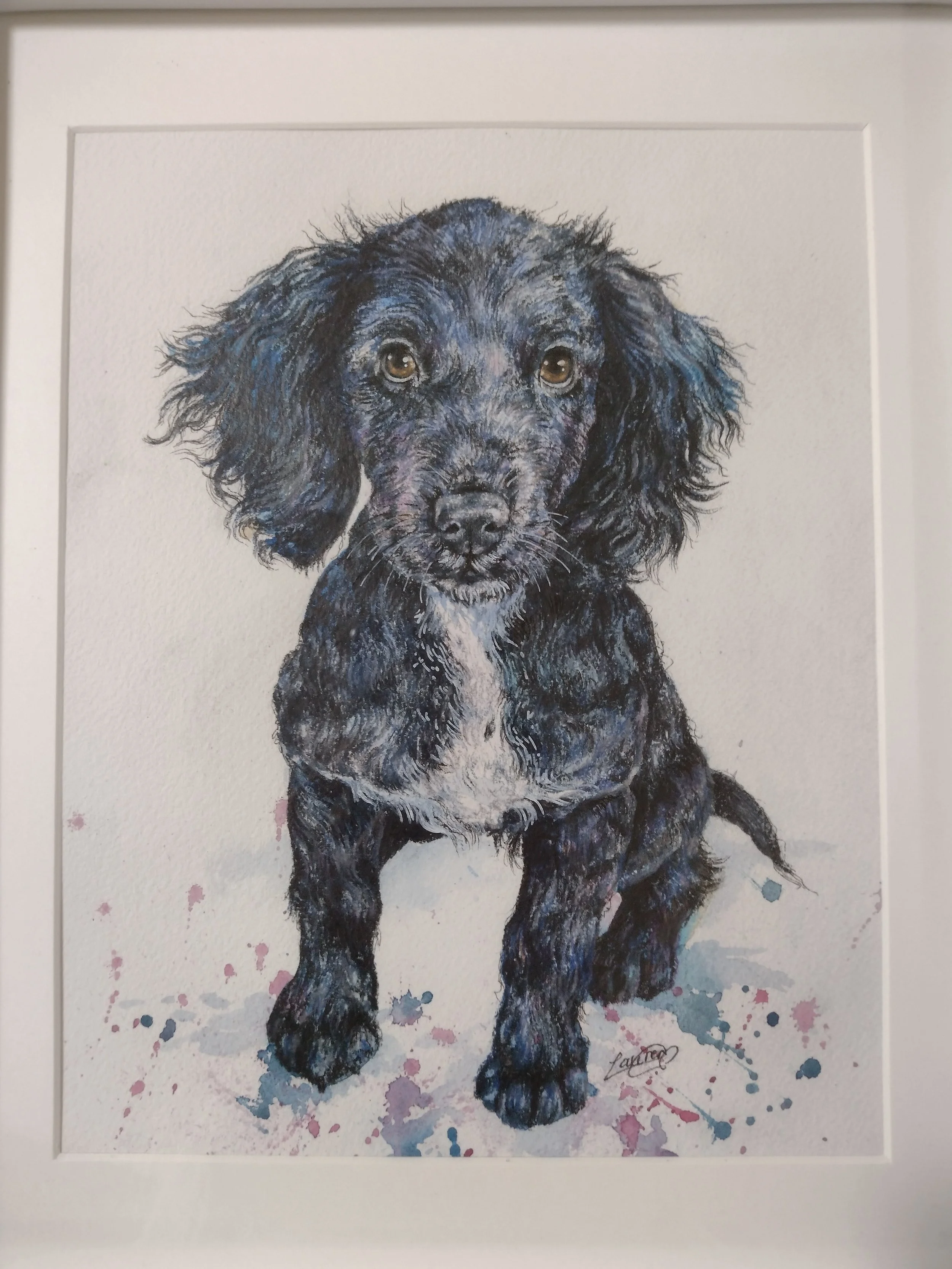 Watercolor painting of a black Labrador puppy with floppy ears, expressive brown eyes, and a white patch on the chest, walking toward the viewer, with colorful splashes of paint around the dog.