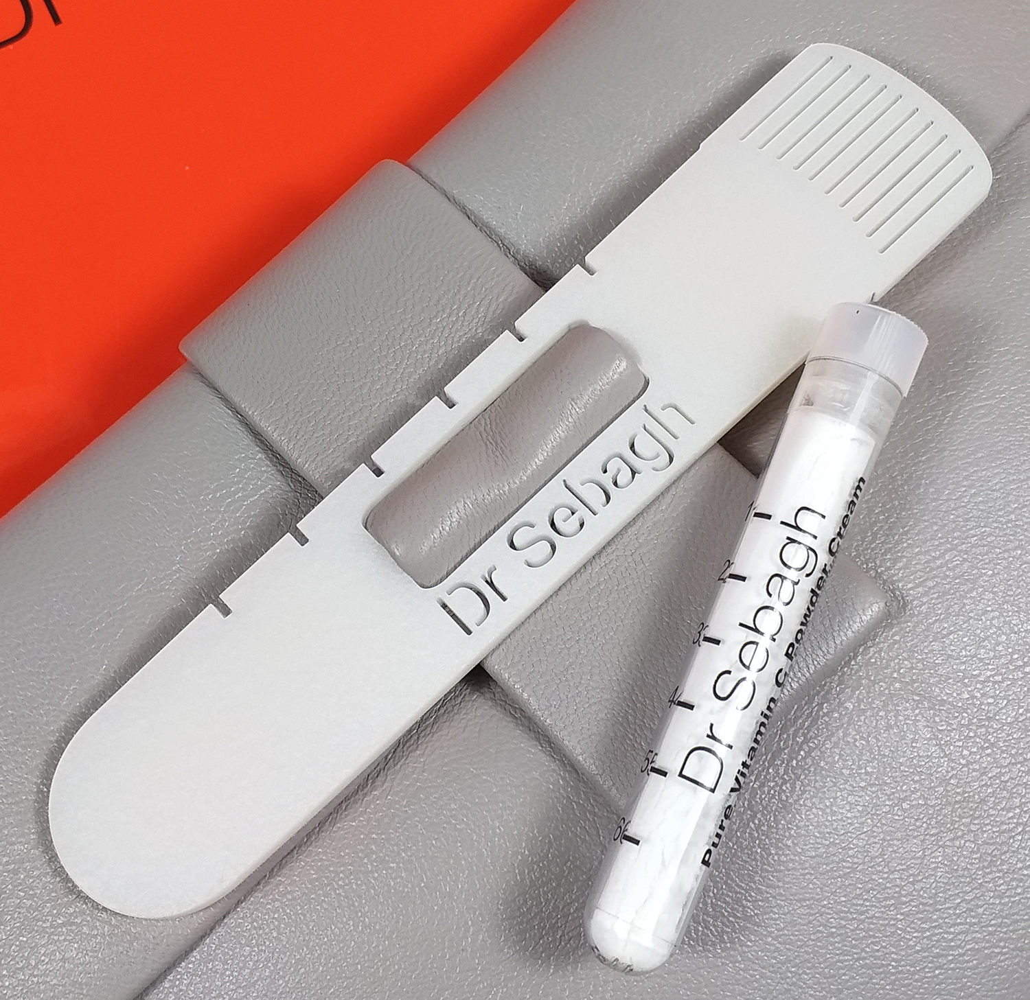 A white plastic sample collection device labeled 'Dr. Sehlab' beside a small tube labeled 'Dr. Sehlab' on a gray surface.