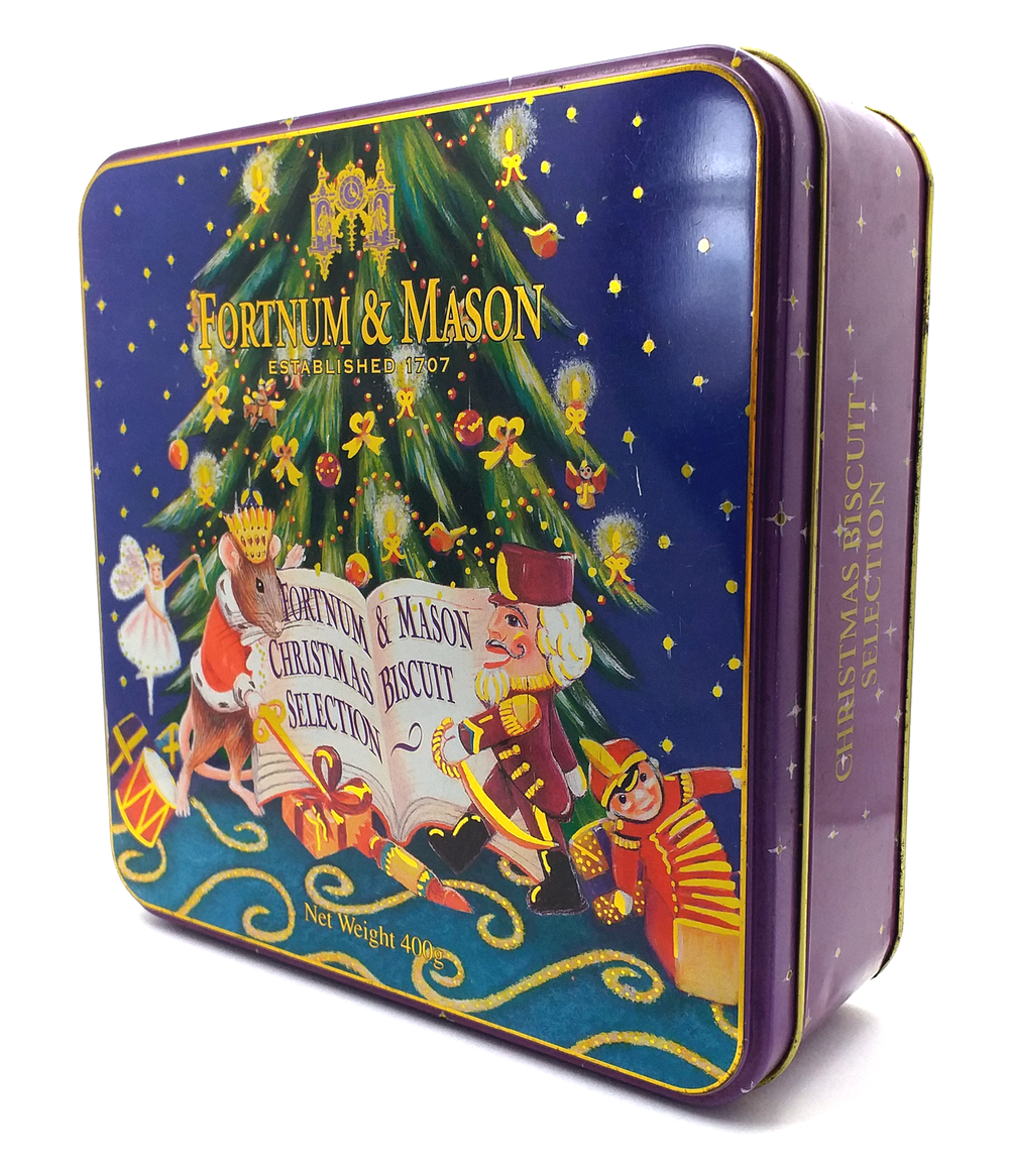 A decorated tin box with a Christmas theme, featuring a Christmas tree, a nutcracker, a mouse dressed as a king, and gifts, with the text "Fortnum & Mason Established 1707" and "Gifts Christmas Biscuit Selection". The box contains 400 grams of biscui