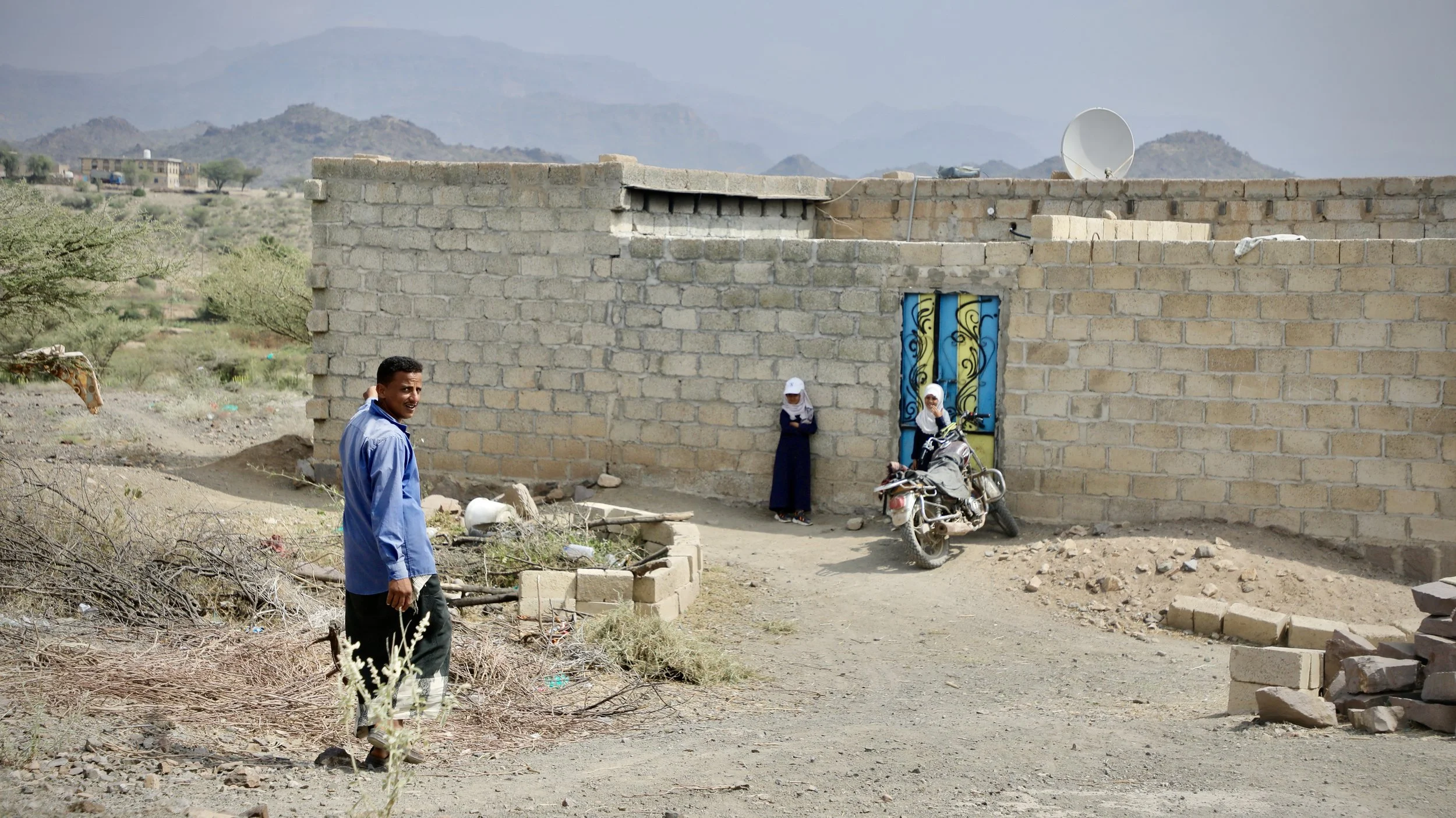 Radwan Mohammed, 35, outside his home in Al Jadanah village, Shakhab, Al Dhale. His daughters Ilham and Iman stand at the doorway behind him. The open ground between them is the perimeter from which Project Masam's Team 18 subsequently cleared 50 Hou