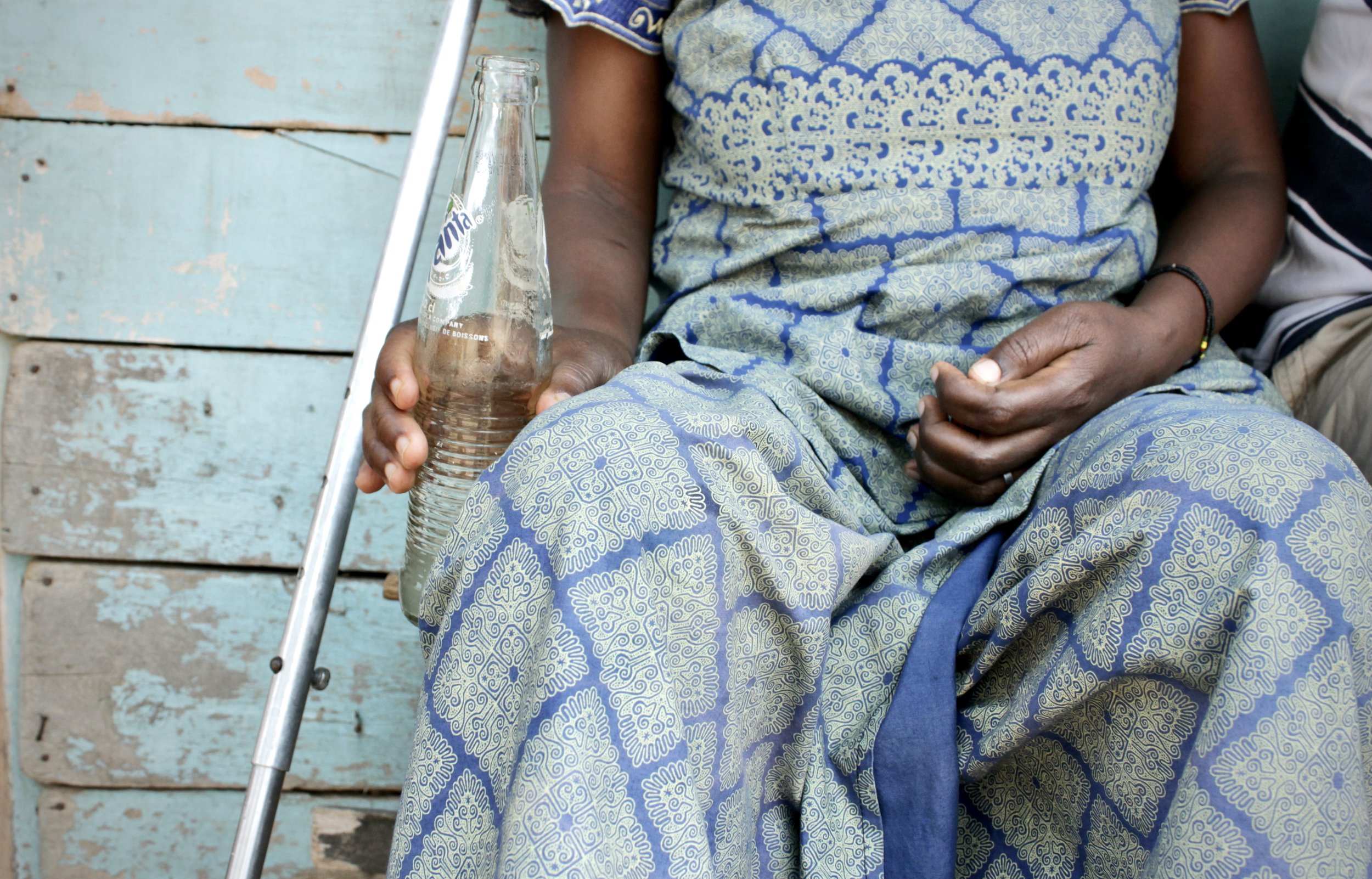 I.N. rests outside a safe location in Bujumbura. After being shot in the thigh, she spent several days receiving treatment before being discharged on crutches. Months later, she continued to experience difficulty walking.