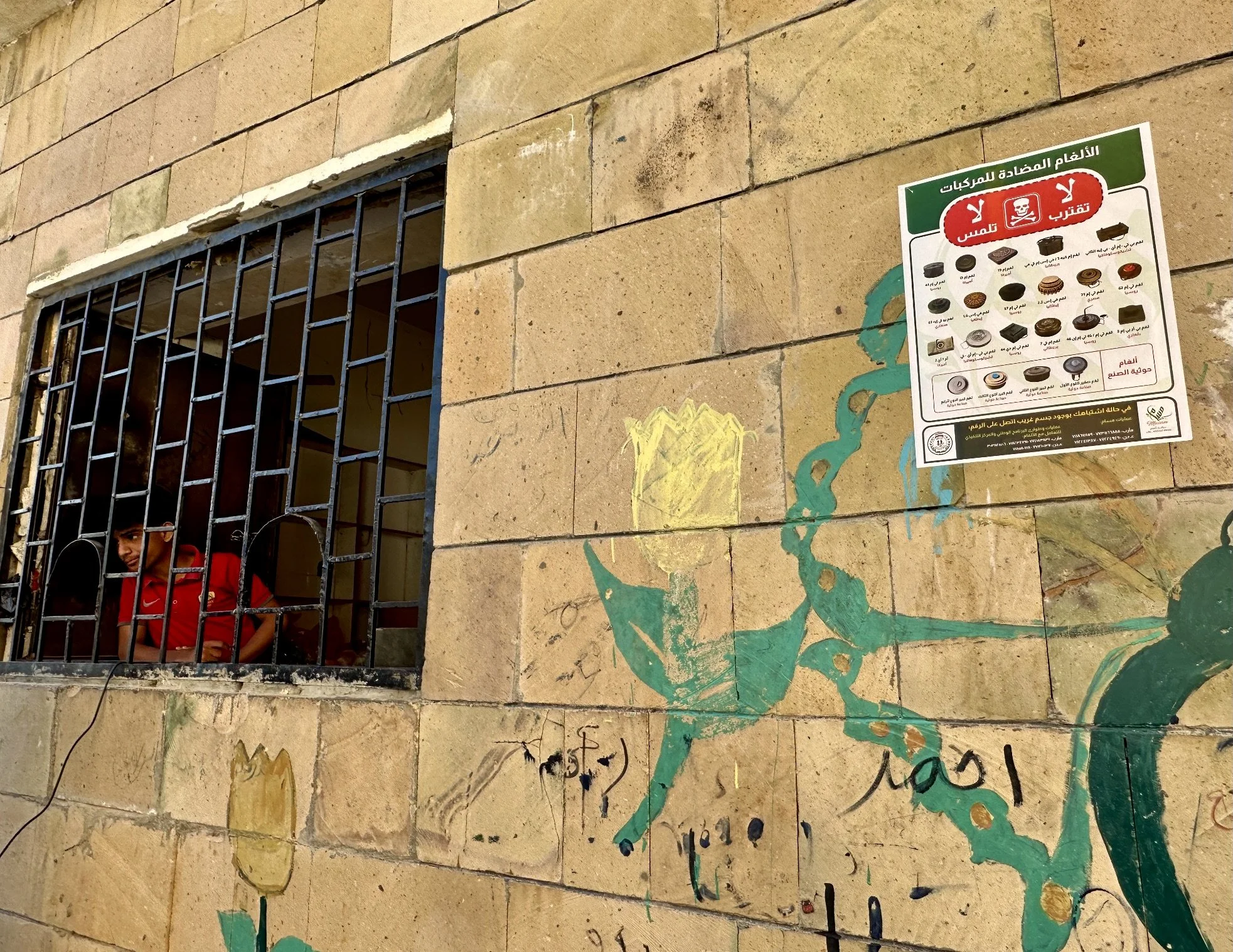 A warning poster showing different types of landmines and improvised explosive devices is displayed on a wall inside Ibrahim Aqeel School in Taiz, Yemen.