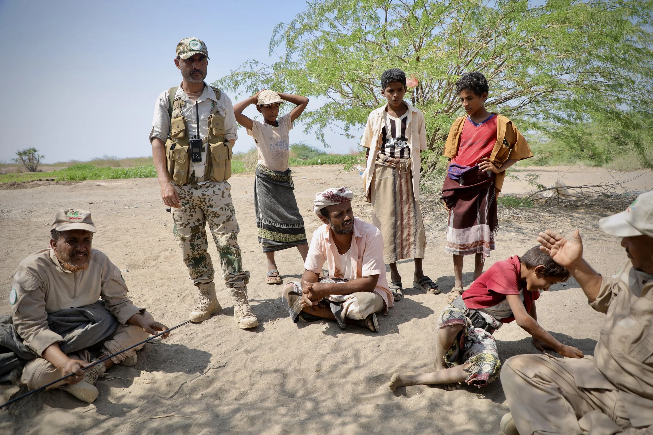 Deminers from Team 21 speak with local residents in Al Remah, near Mocha, Taiz governorate, Yemen. Conversations like these form part of informal Explosive Ordnance Risk Education (EORE), where information about suspected hazards and recent incidents
