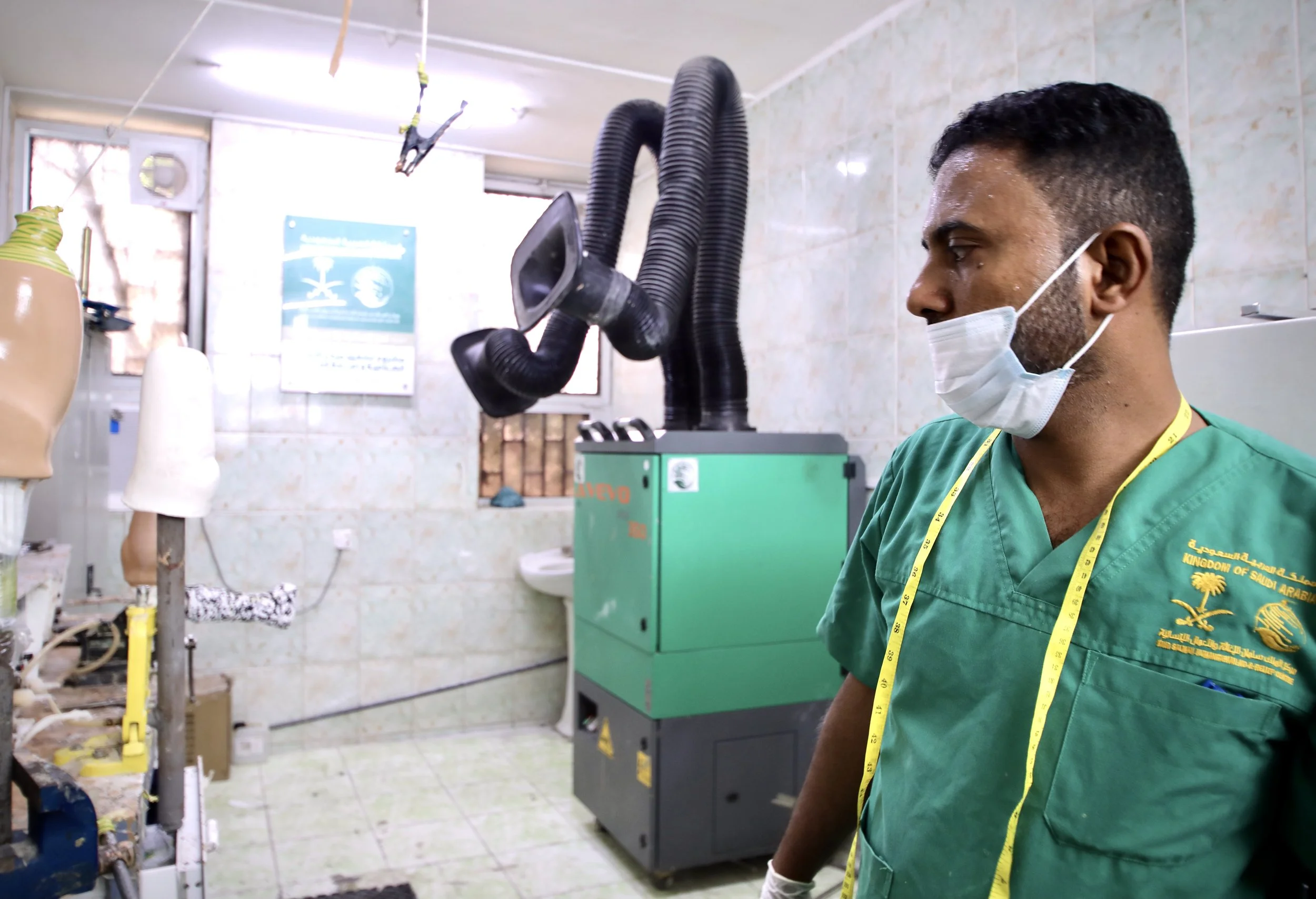 A technician waits beside a heating unit used to harden plastic prosthetic components inside the workshop at the rehabilitation centre in Aden, Yemen.