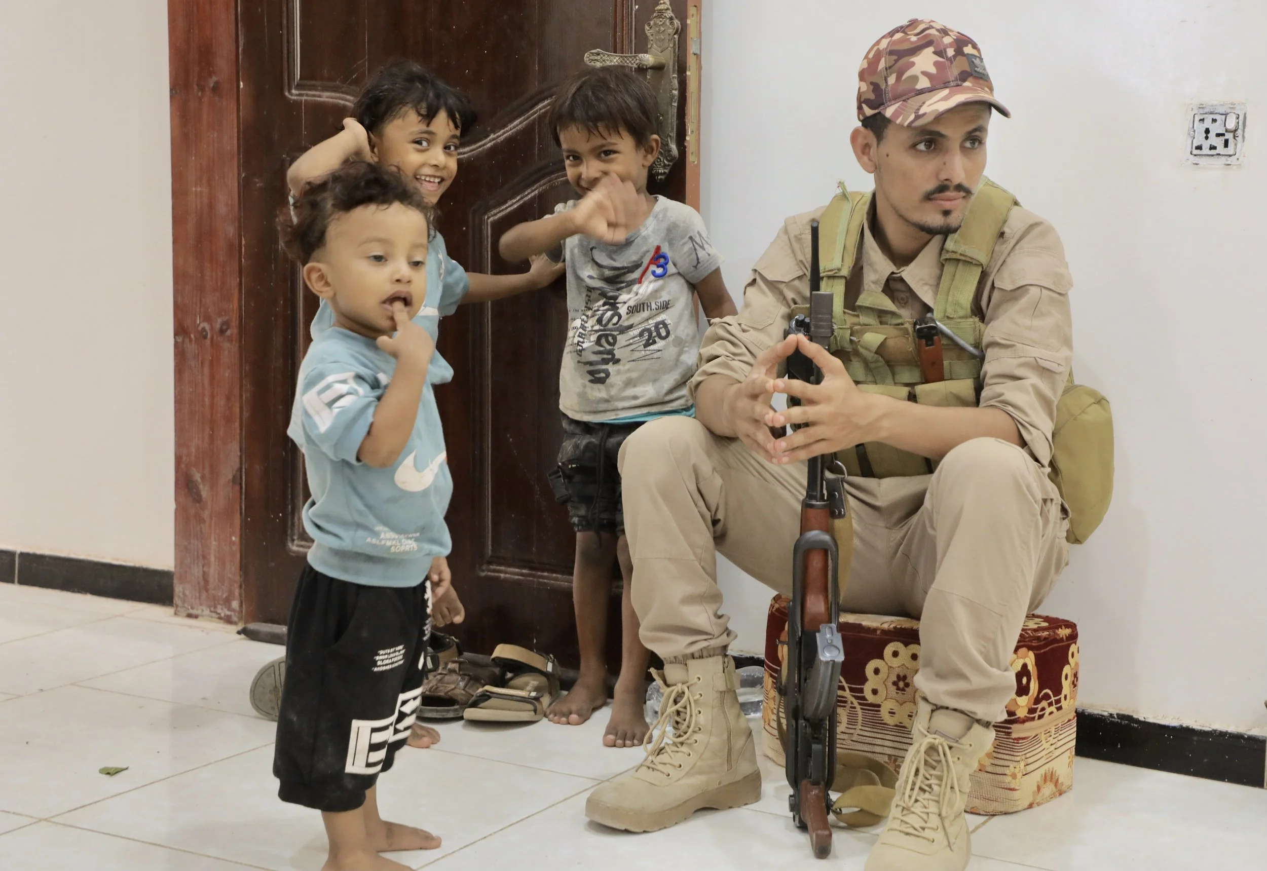 A security guard speaks with children inside the family home while waiting for Sami to return from work.