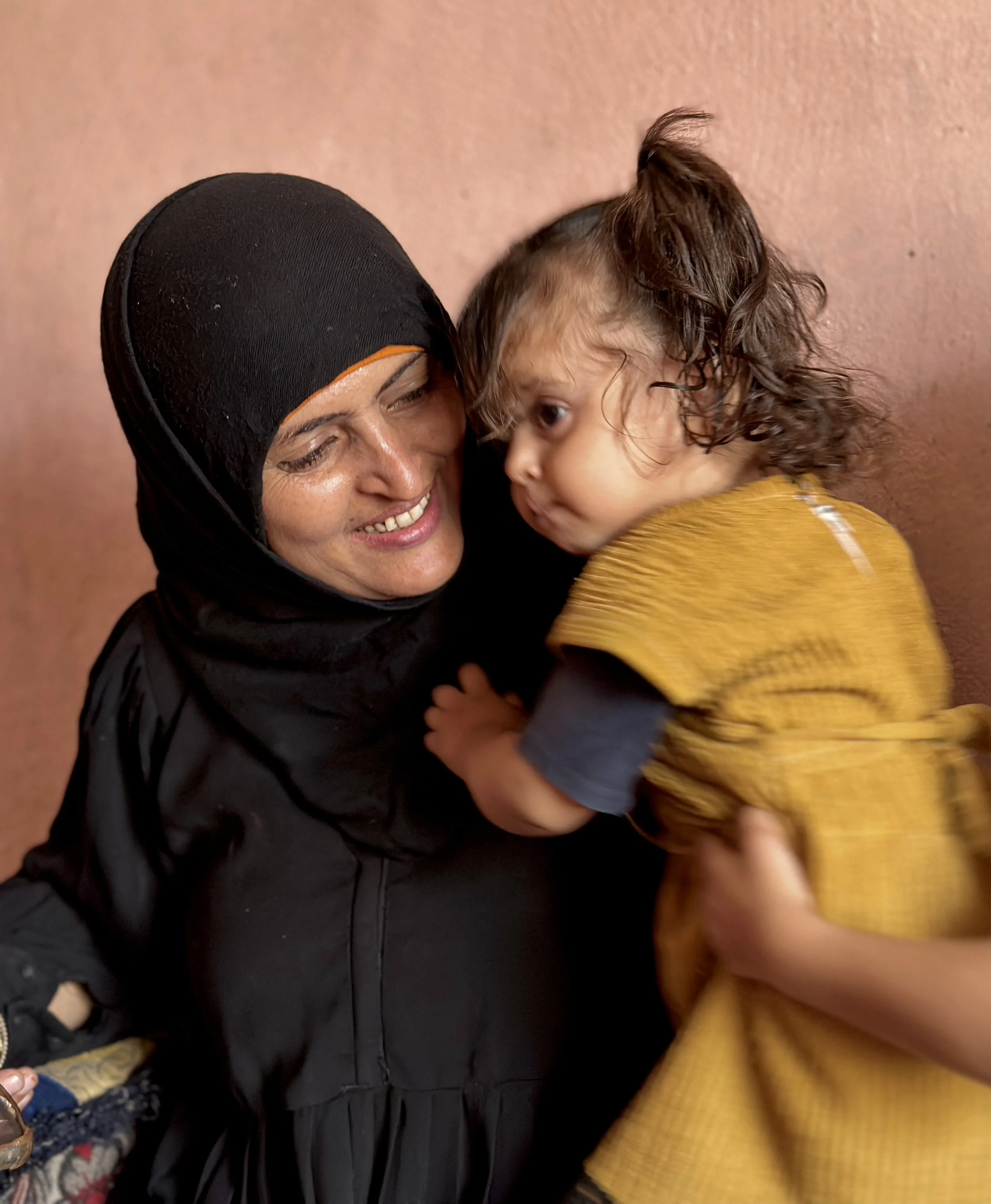Dalila Abdo Ahmed holds a young relative inside her family home in Taiz. In Yemen, women living with disabilities often face stigma and social isolation after conflict-related injuries. Dalila says she has accepted life outside marriage and instead p