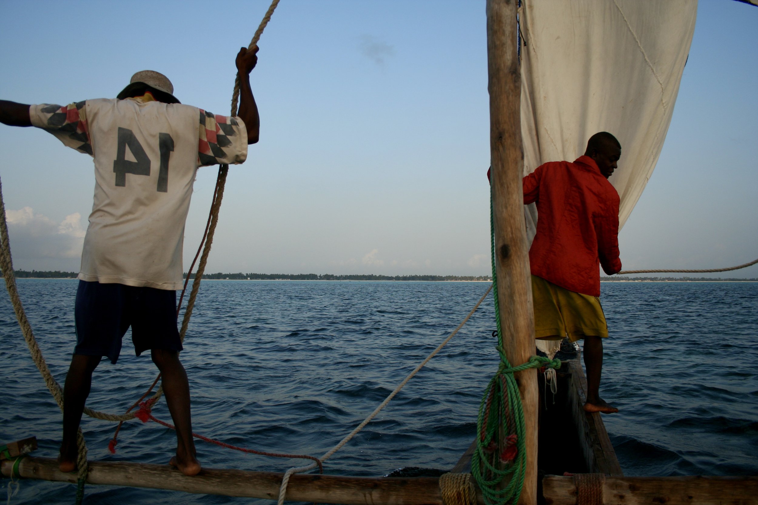 Captain Fruit and a crewman haul the canvas sail into position as the dhow prepares to leave the shallows.