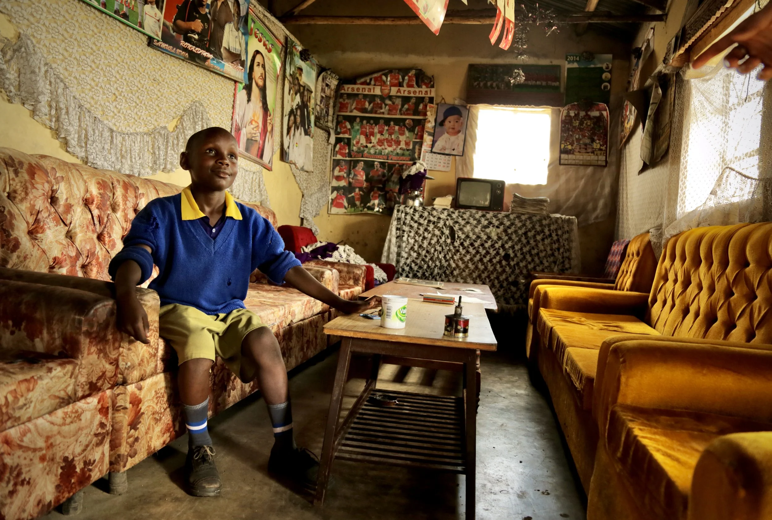 A pupil sits inside his family's living room in Kakamega County, Kenya. Time spent collecting water can reduce the hours available for homework, study and rest.