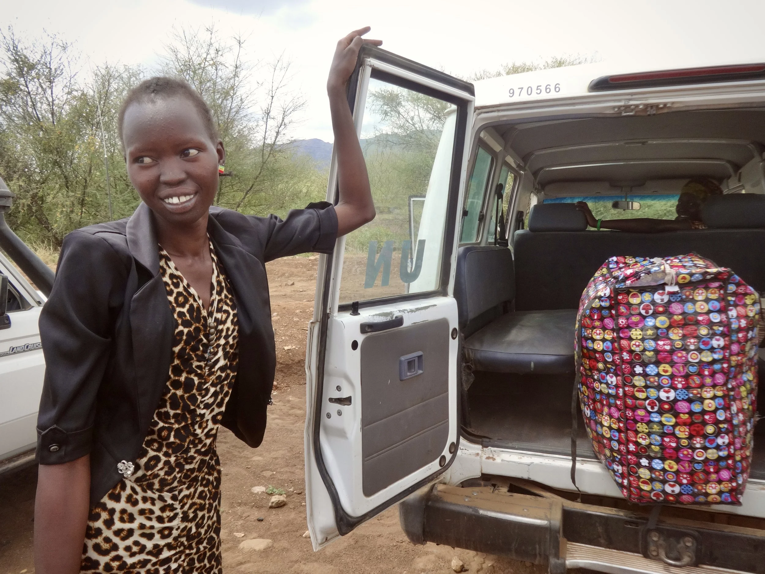 Randa stands beside a UNHCR vehicle that will transport her to Kakuma refugee camp after being granted entry into Kenya - a two-hour drive.