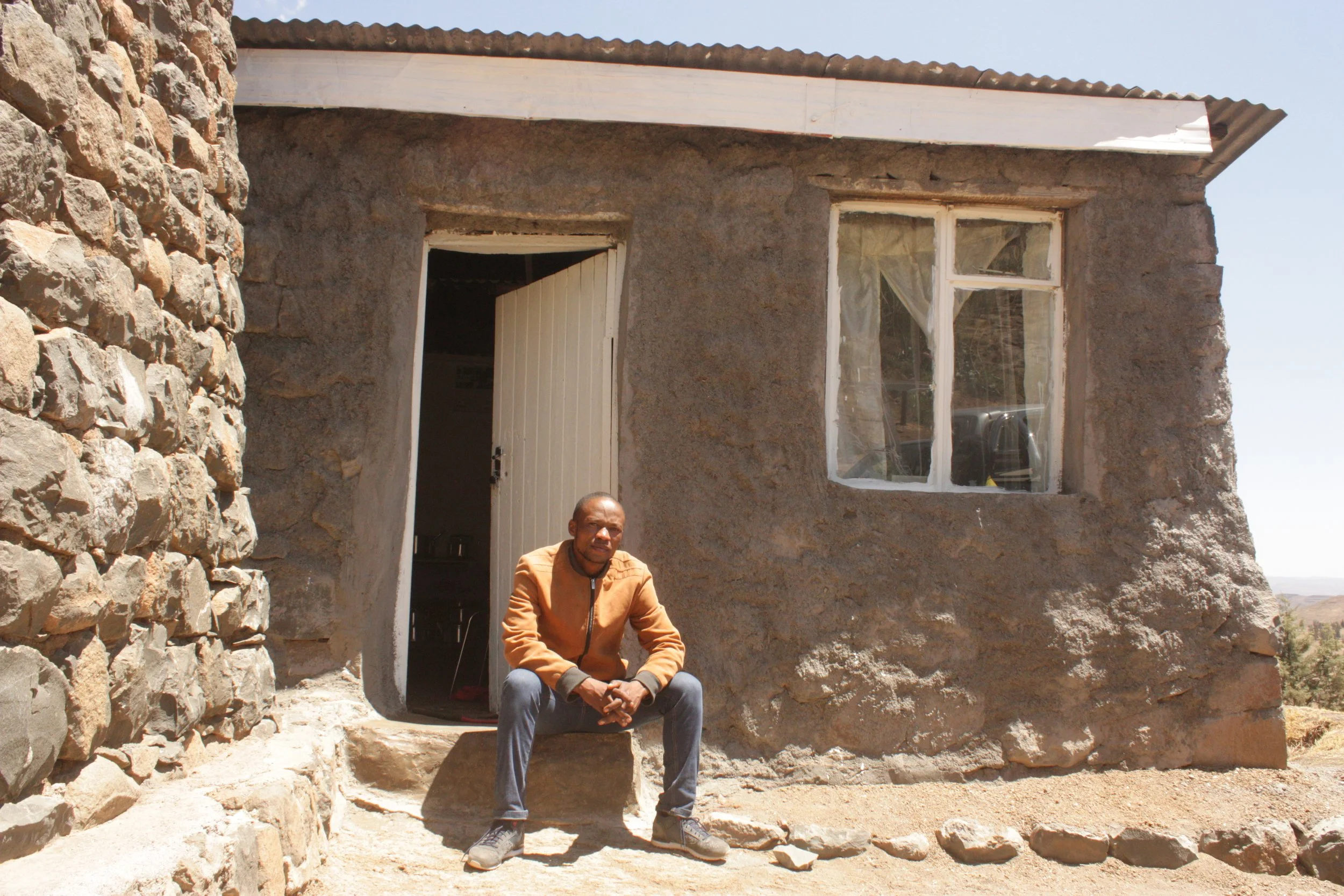 Pheto sits outside his home in Ha Makunyapane. Reaching the village requires hours of travel through Lesotho’s mountainous interior, where many communities remain geographically isolated from public services.