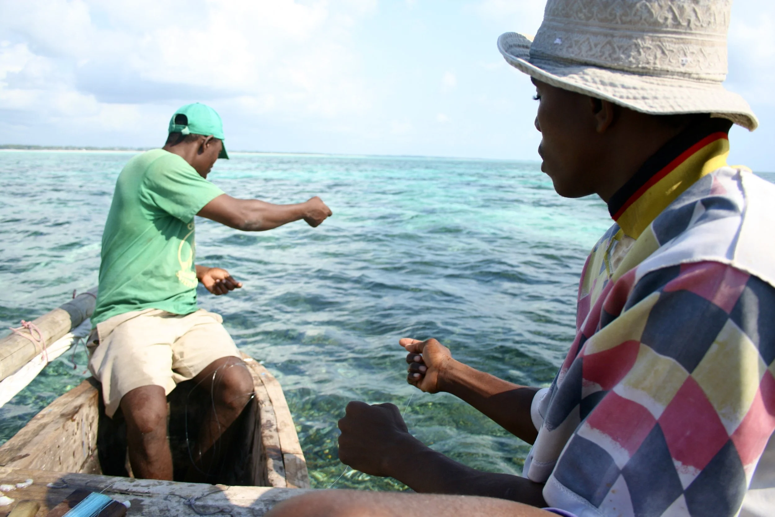 Two fishermen work their lines against the turquoise shallows of the reef.