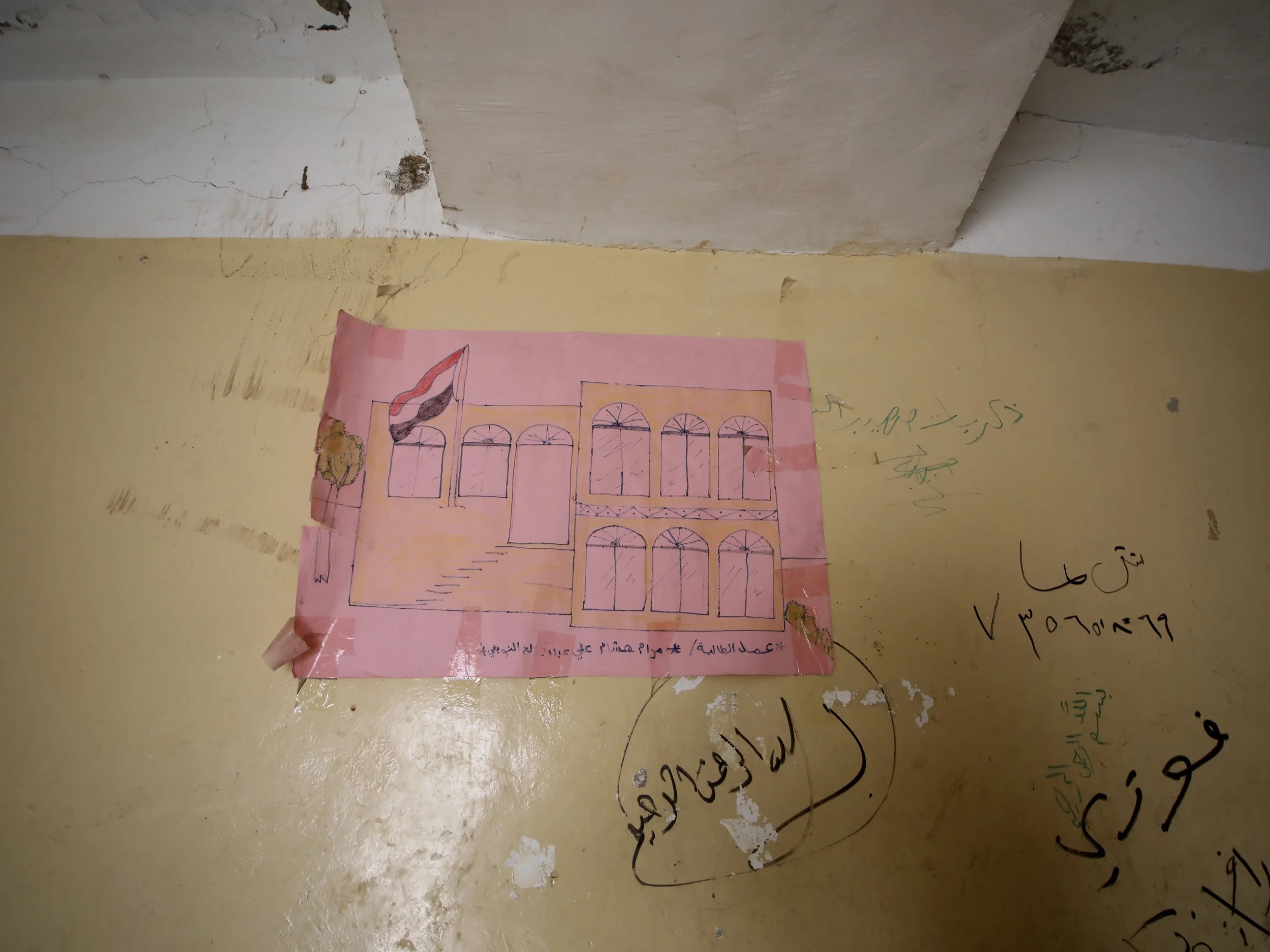 A child’s drawing inside Al Shaab School depicts the building before part of it was destroyed during the conflict.