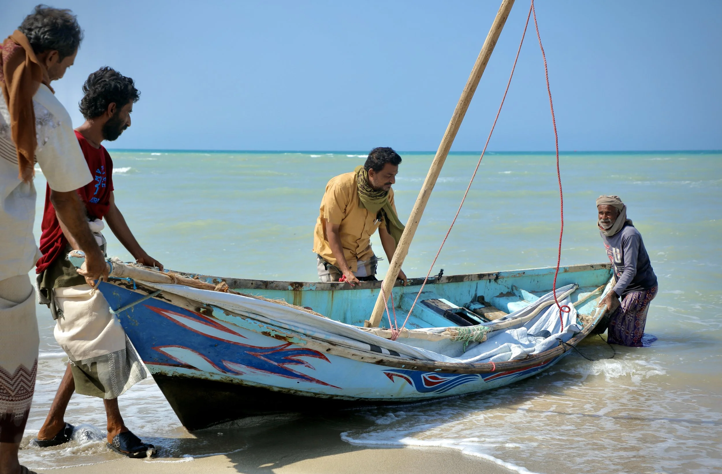 Fouad Ali Abdullah Dubalah, General Secretary of the Al Mostaqbal Fishery Association, speaks with fishermen along the shoreline in Al Khokha, where communities rely on constant information-sharing to avoid mined areas and dangerous waters.