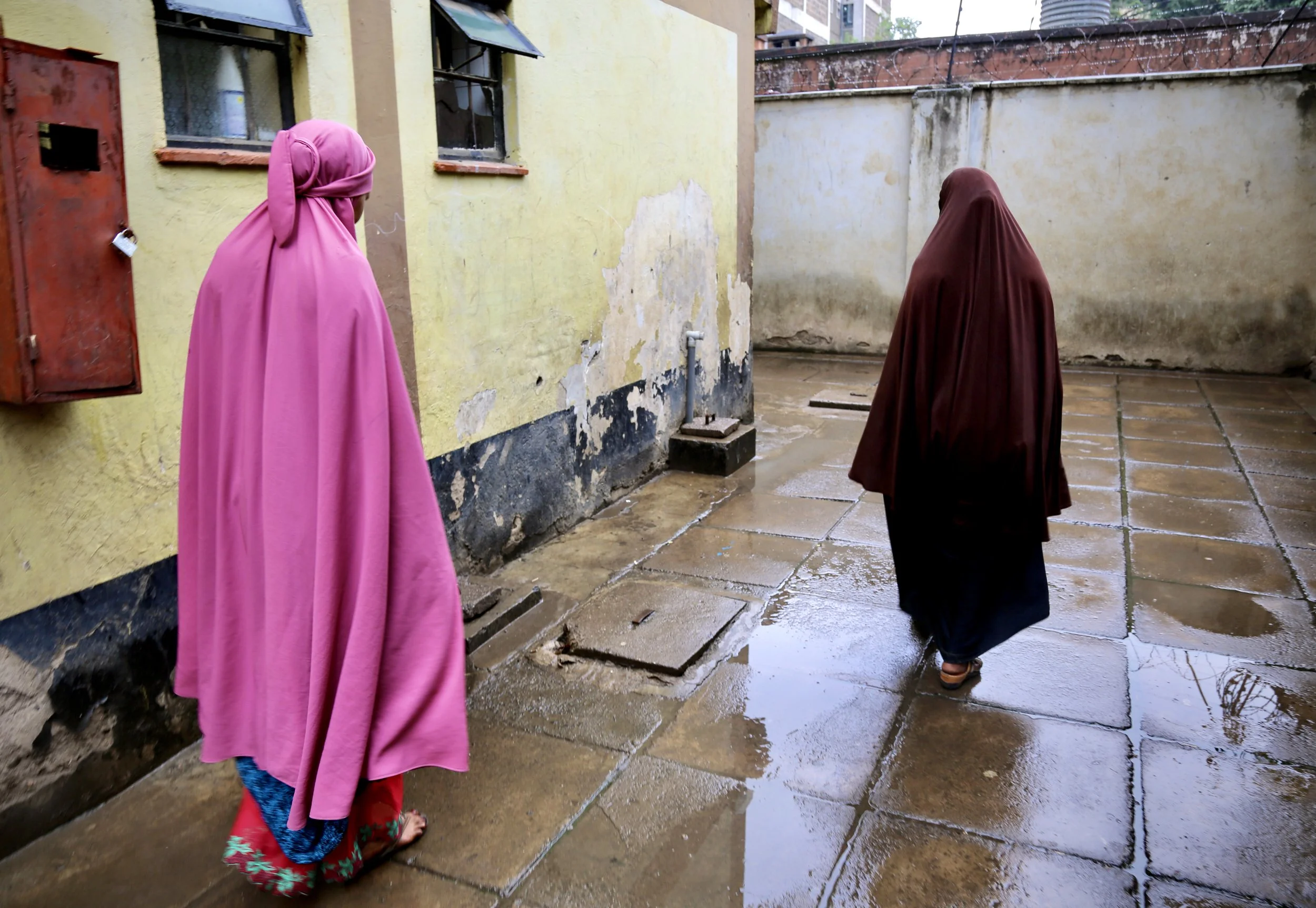 Somali refugee women walk through the courtyard of an apartment building in Eastleigh, Nairobi. Refugees described feeling trapped between insecurity in the camps and fears of detention or deportation in the city. Nairobi, Kenya, June 2016.