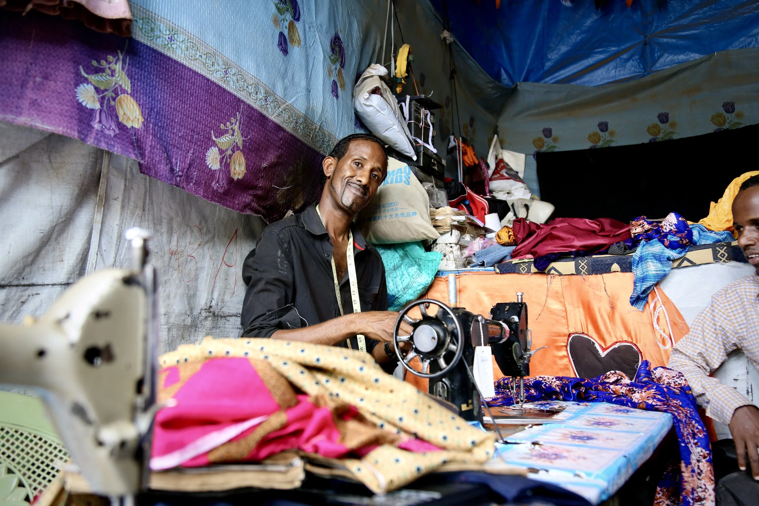 The tailor in his workshop. He learned the craft through skills practiced by women in his family.