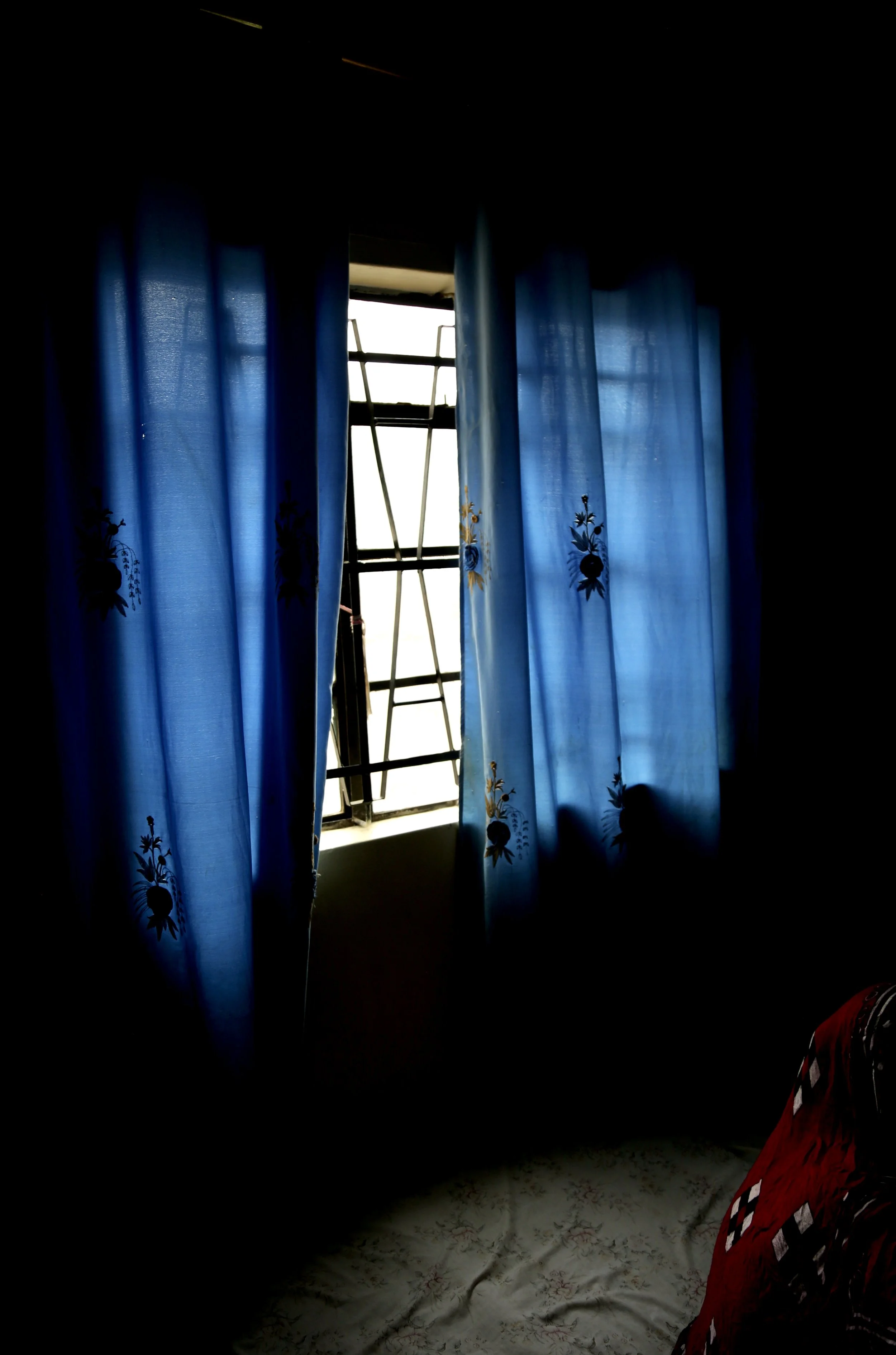 Light enters through a curtained window inside an apartment in Eastleigh, Nairobi. The sisters said they rarely ventured outside because they feared arrest, detention or deportation. Nairobi, Kenya, June 2016.