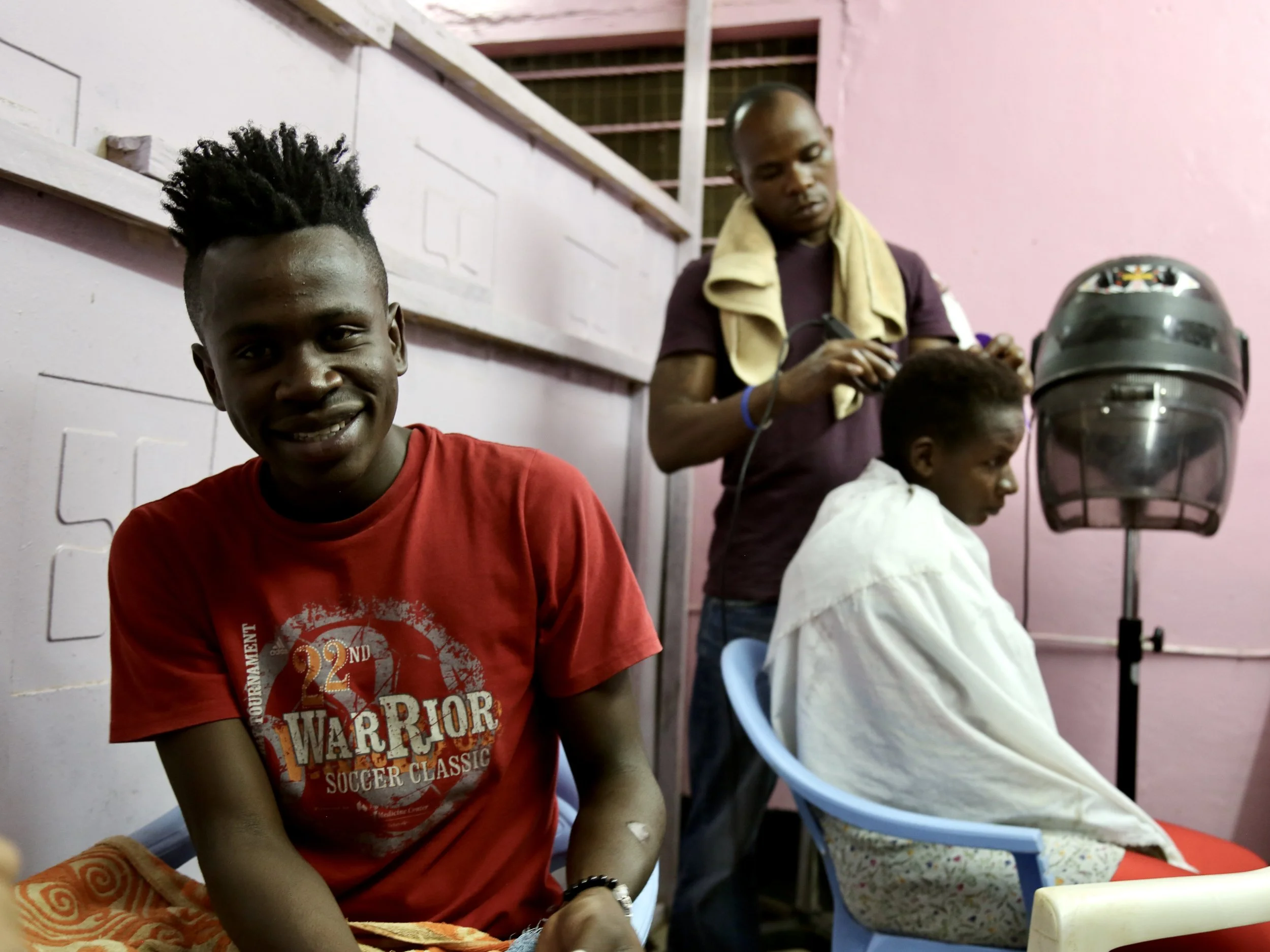 Young men gather in a salon as one has his hair cut in Kakuma refugee camp.
