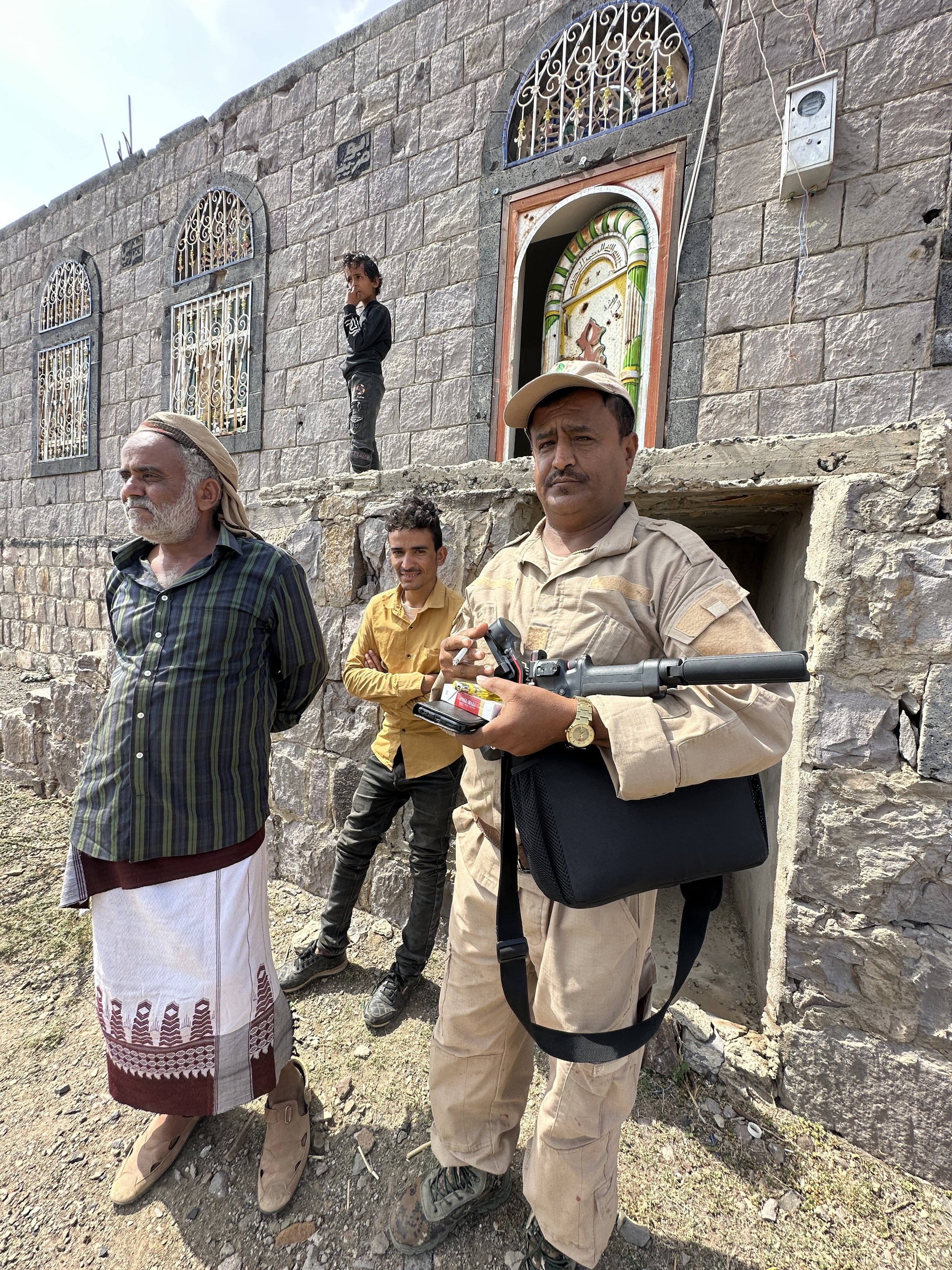 A Project Masam deminer catches up with local residents outside a home in Shakhab, Al Dhale, at the end of a working day. Project Masam's teams are on first-name terms with the families whose land they clear.
