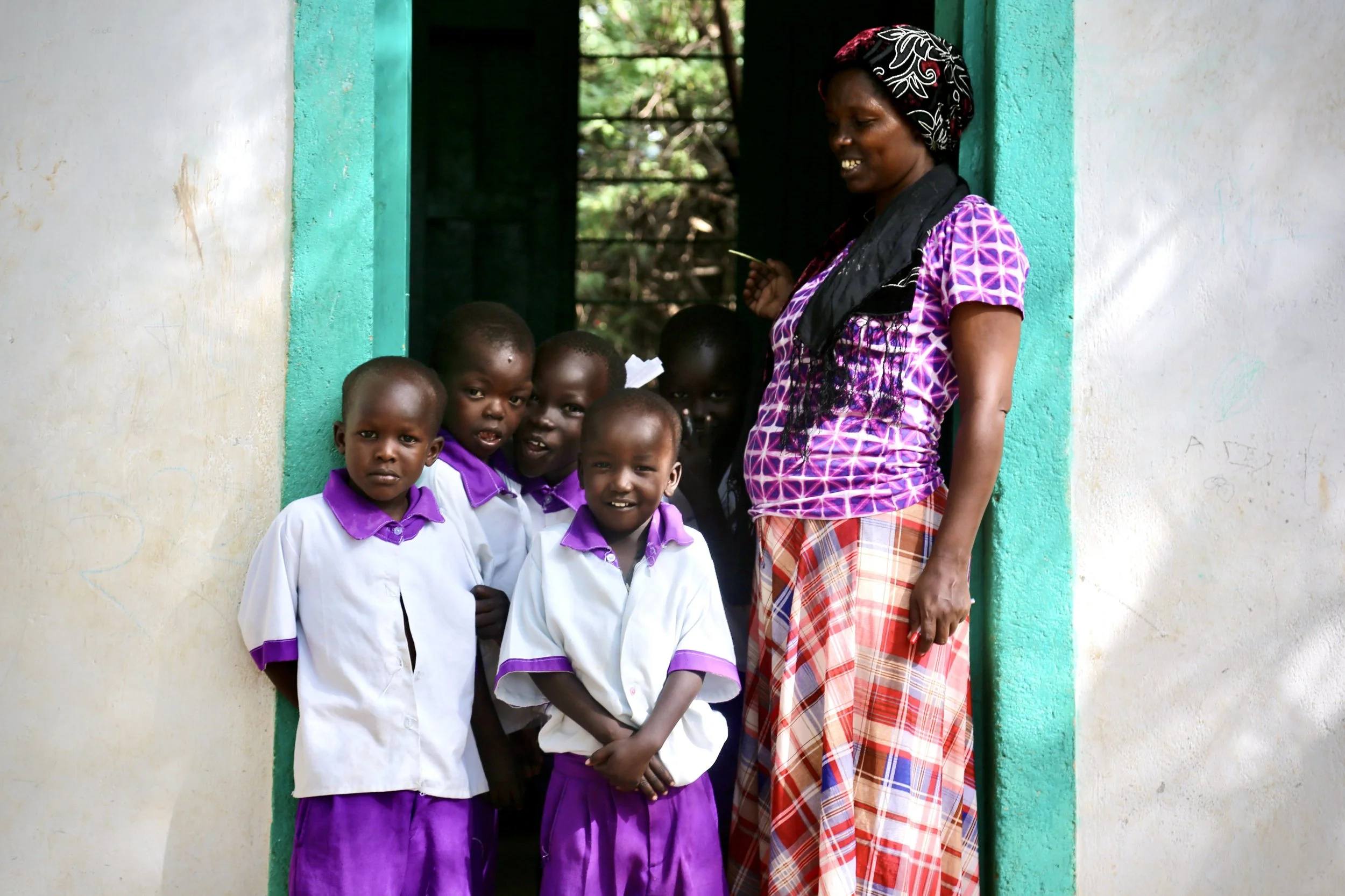 A resident stands with children at the entrance to the Safe Haven, where mothers and children facing protection risks could live under close supervision.