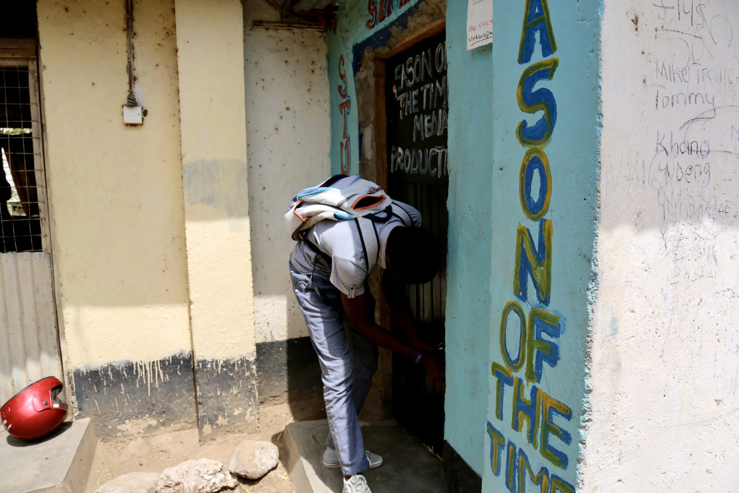 Fidele Wabenga enters his studio workspace in Kakuma Refugee Camp. From this small room, he built a photography and film business serving the community.