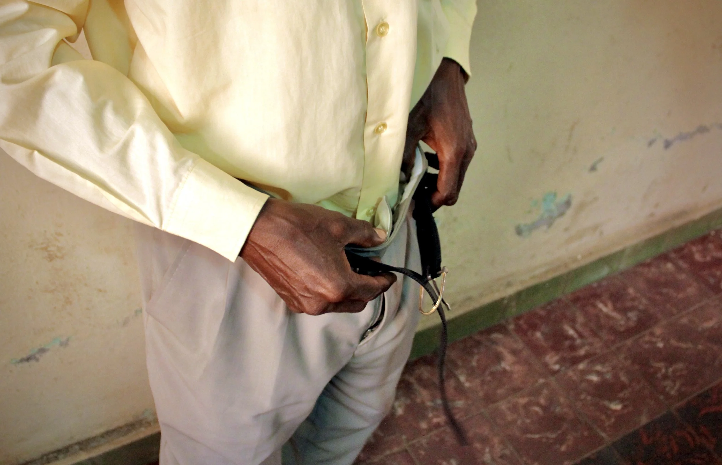 P. Sinzinkayo fastens his belt after documenting injuries he alleged were sustained during torture in detention. The simple act of dressing caused visible pain. Weeks after his release, he was still struggling with the lasting effects of his injuries