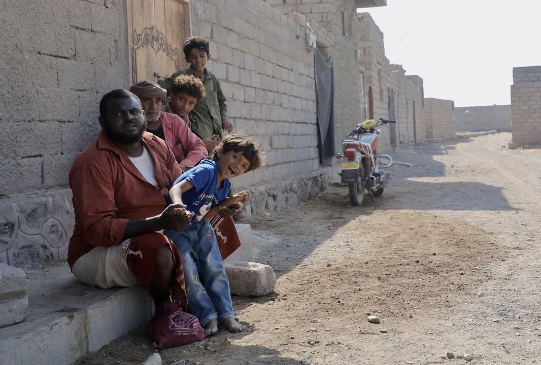 Residents gather outside their homes in a village north of Al Khokha, near heavily contaminated frontline areas.