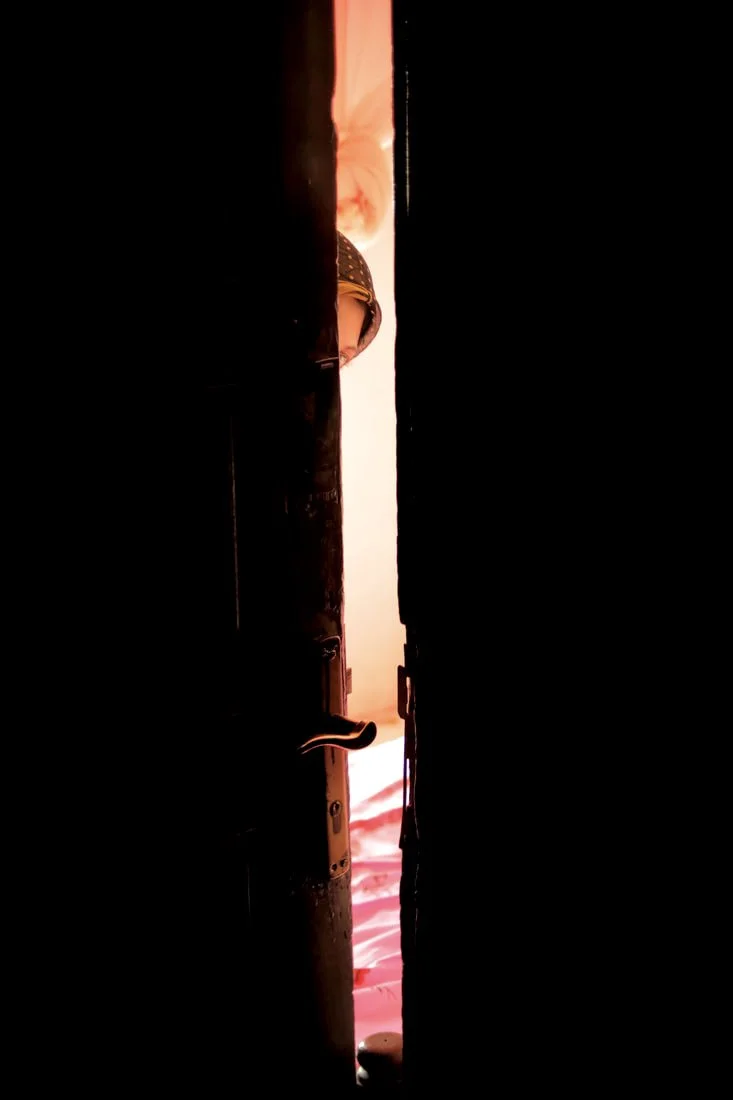 Dalila Abdo Ahmed peers through the doorway of her family’s apartment in Taiz, Yemen. In 2018, Dalila lost both legs below the knee after stepping on a landmine on the morning of her wedding while trying to reach her husband’s family home near the fr