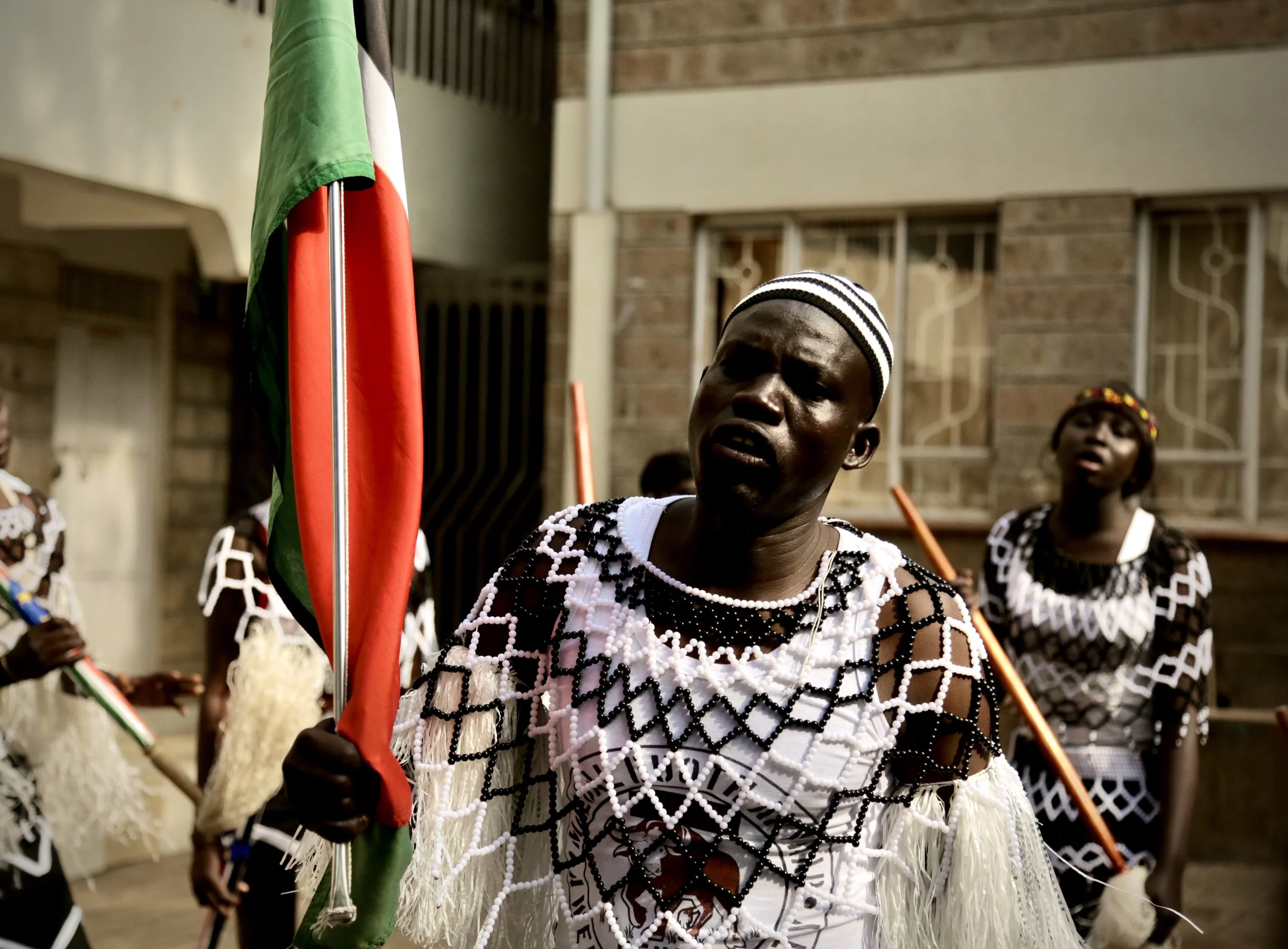 A refugee performer carries the South Sudan flag during a cultural procession at Divine Word Church in Kayole, Nairobi, as part of World Refugee Day celebrations.