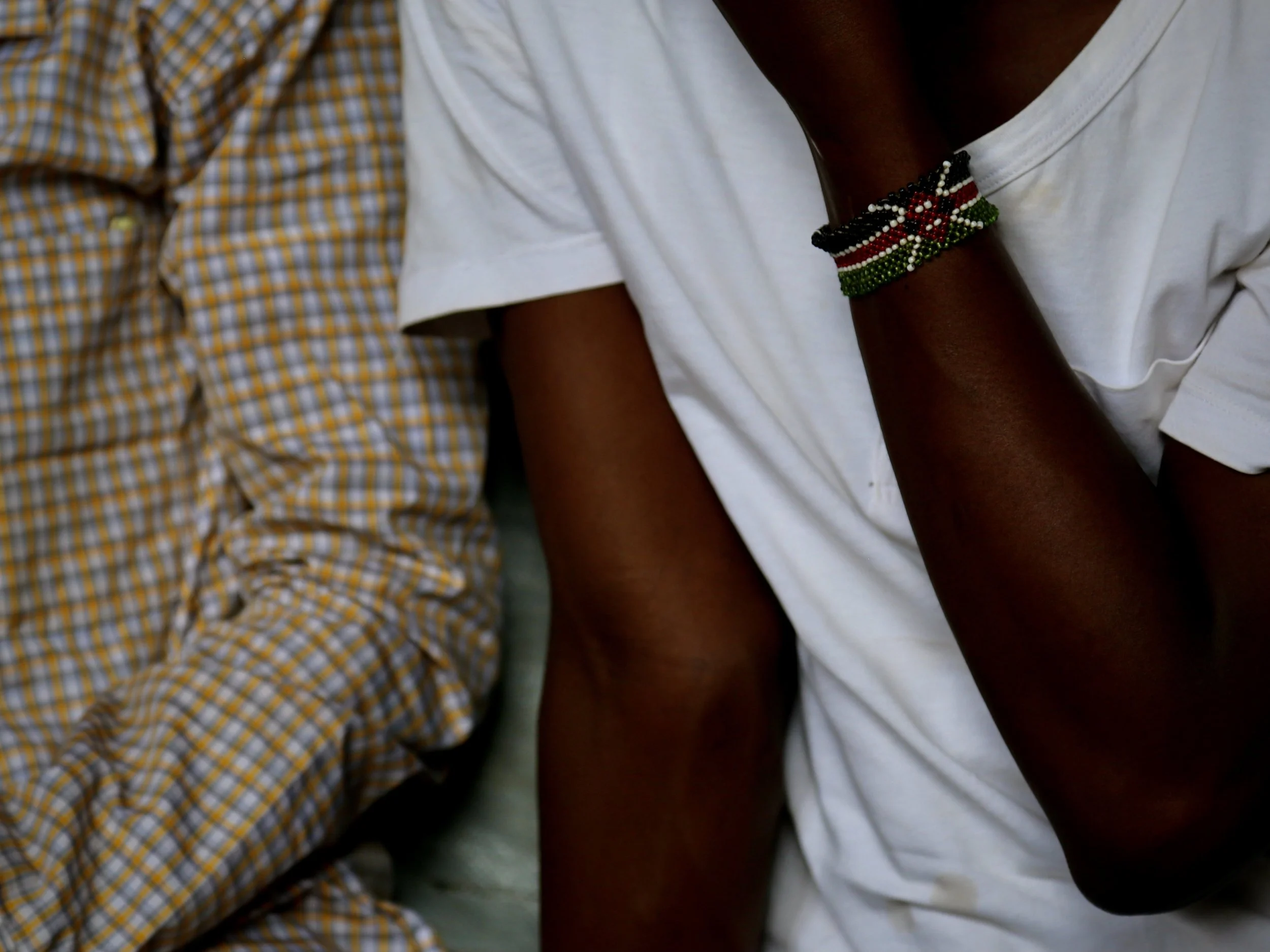 A young man from South Sudan wears a bracelet in the colours of Kenya while spending time in the shop.