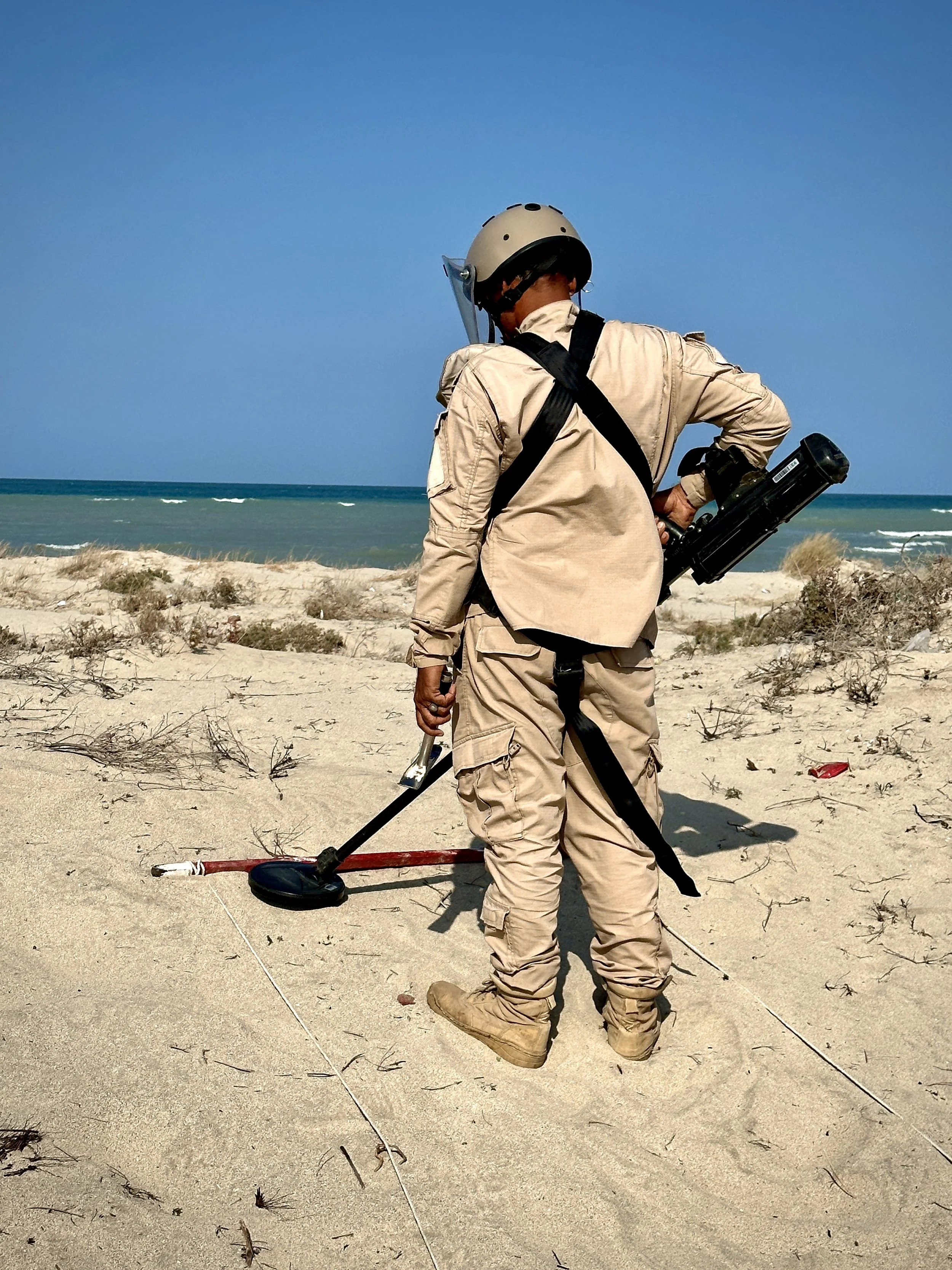 A deminer from Project Masam’s Team 26 searches for explosive devices along Yemen’s western coastline, where mines remain buried beneath sand and coastal vegetation.