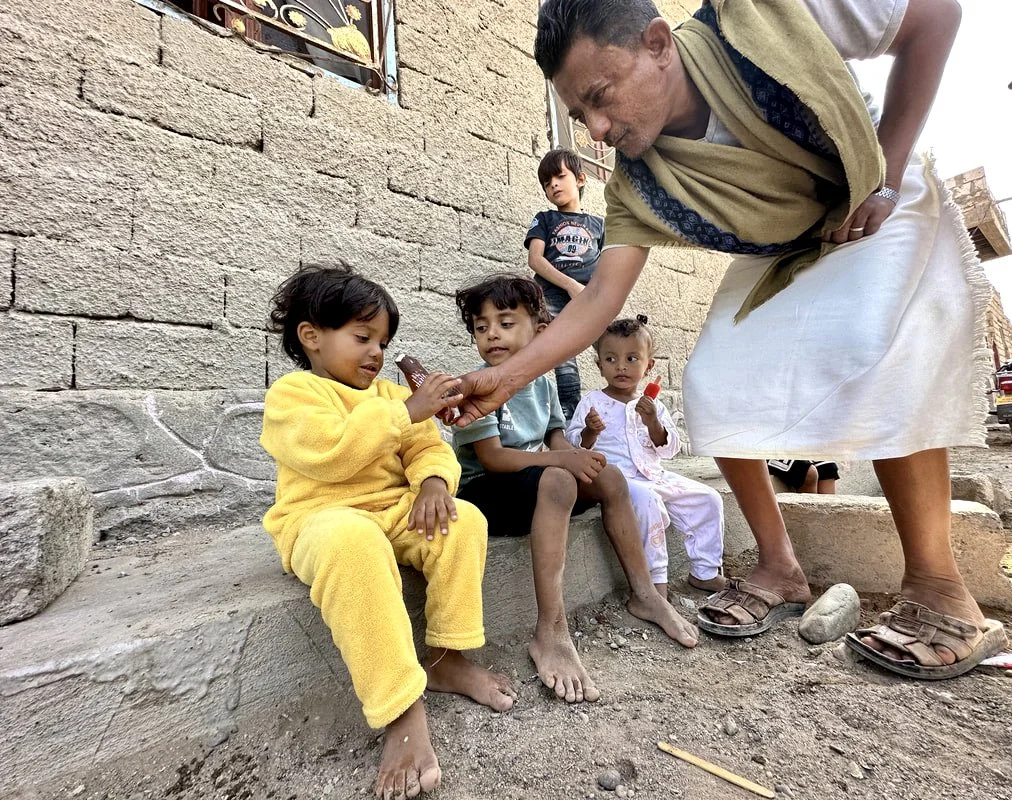 The children’s grandfather Saeed Omar Haimed hands out ice cream outside the family home.