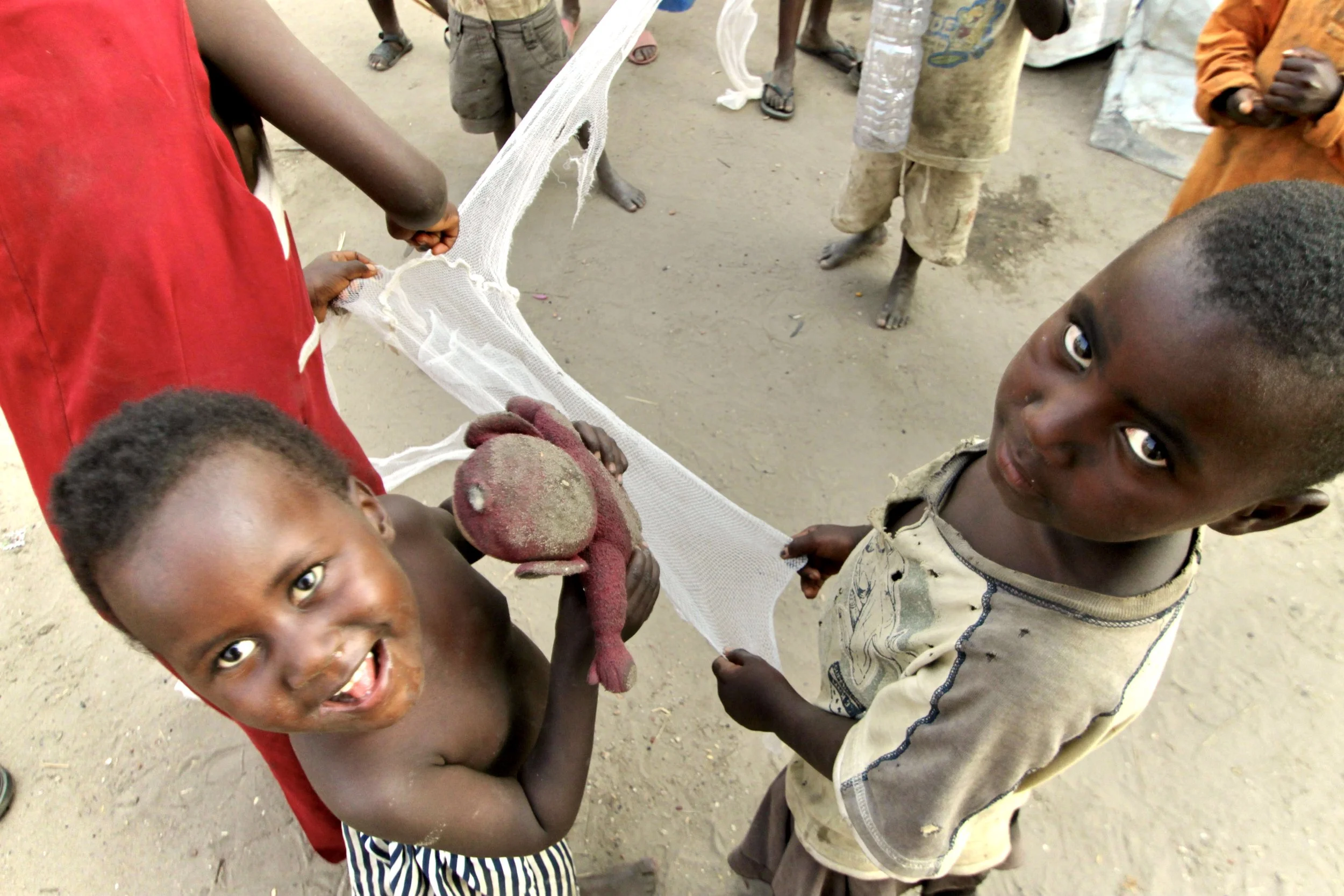 Children play with improvised toys made from discarded and found materials inside the camp, where families displaced by violence adapted daily life with limited possessions and resources.