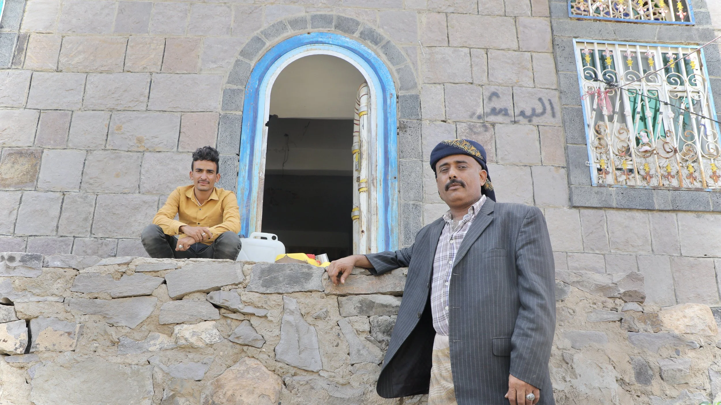 Saleh Abdullah Qassem at the entrance to his home, Qatabah, Al Dhale Governorate, with a member of his family. Members of the Qassem family were killed and injured by landmines and booby-traps planted inside this compound during the war.