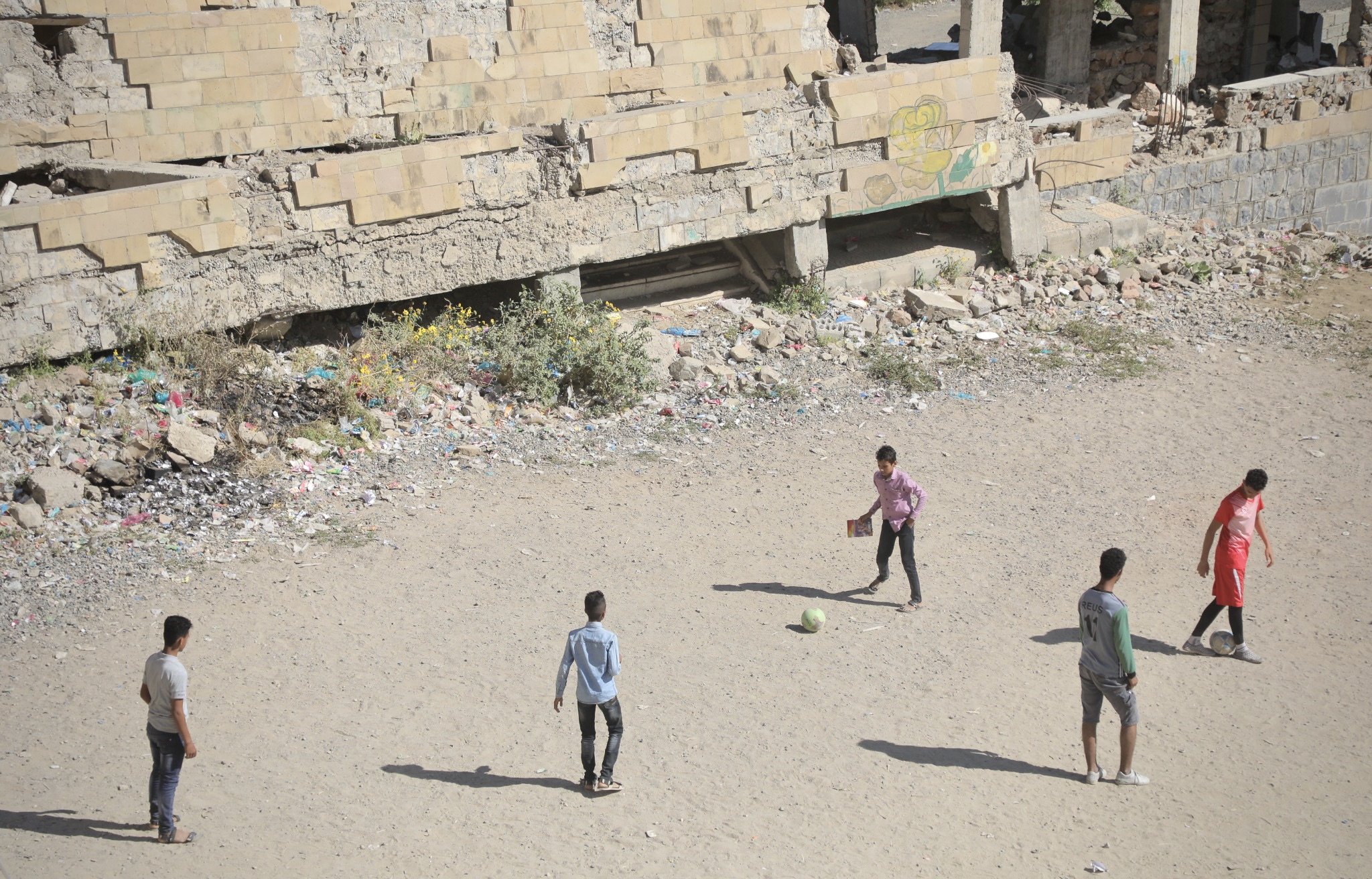 Children play football in the yard of Ibrahim Aqeel School in Taiz, Yemen, as school life continues despite years of conflict and damage to the campus.