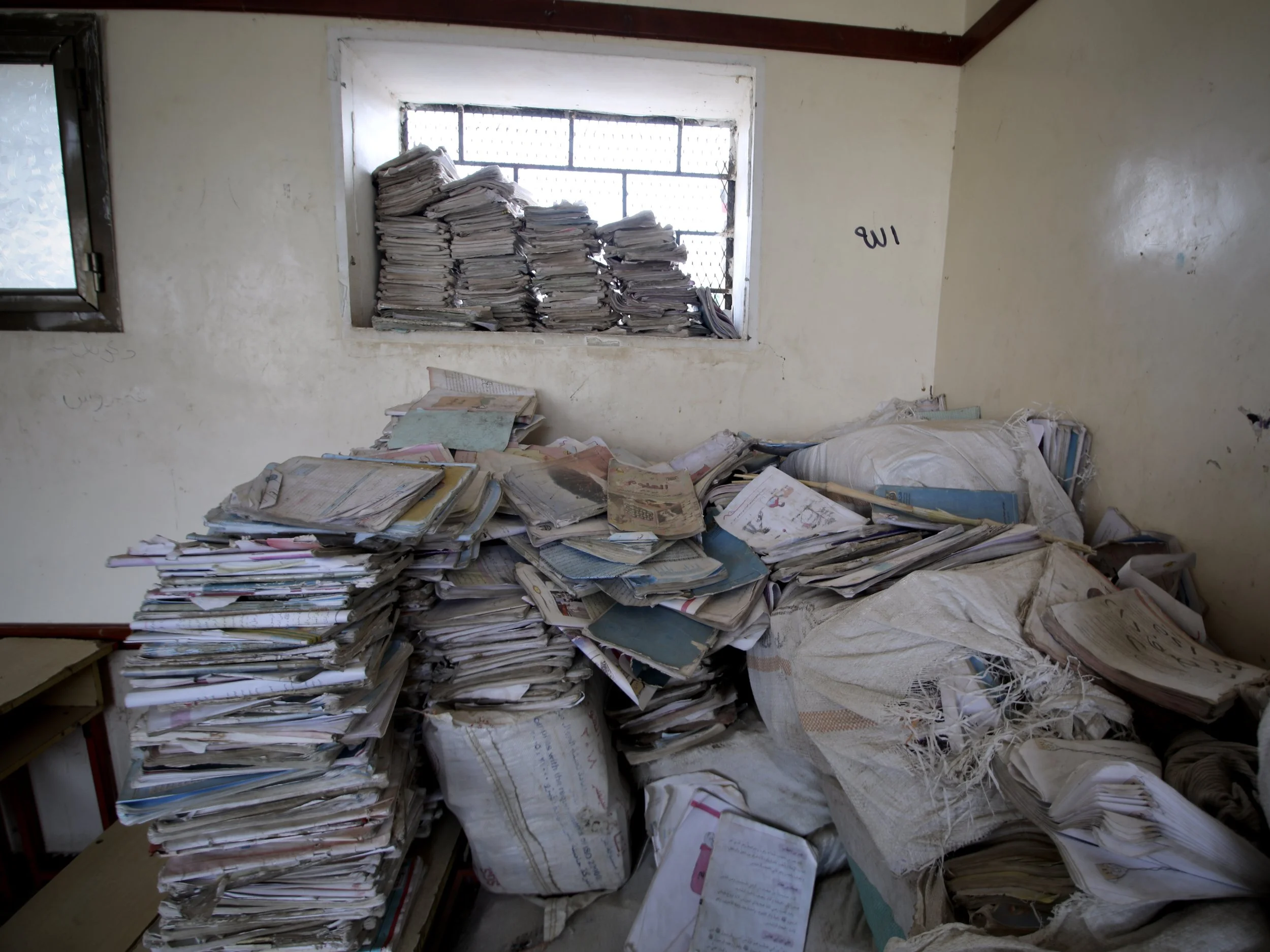 Damaged schoolbooks and teaching materials remain piled inside Al Shaab School years after parts of the building were destroyed during the conflict.