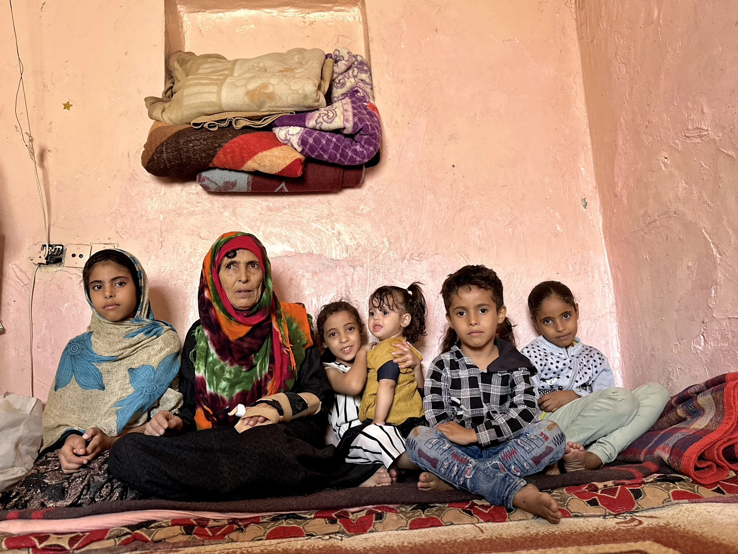 Dalila's mother Qoboul Ahmed Al-Hajj, 70, sits with her grandchildren inside Dalila's apartment in Taiz. Three relatives in the extended family live with disabilities caused by landmine explosions, while Dalila says the family also lost four uncles a